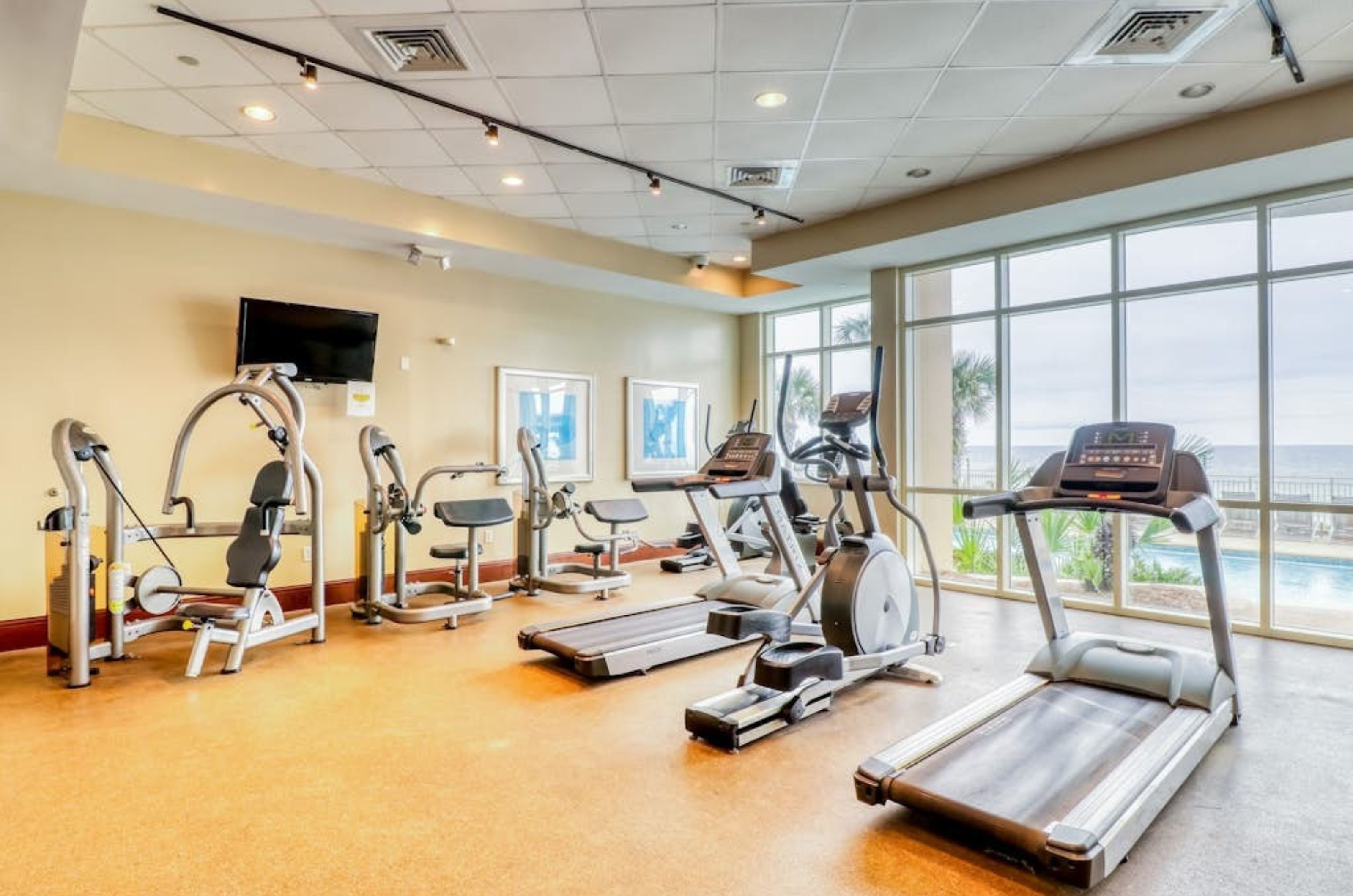 Strength and cardio equipment next to windows in the fitness center at Aqua Resort