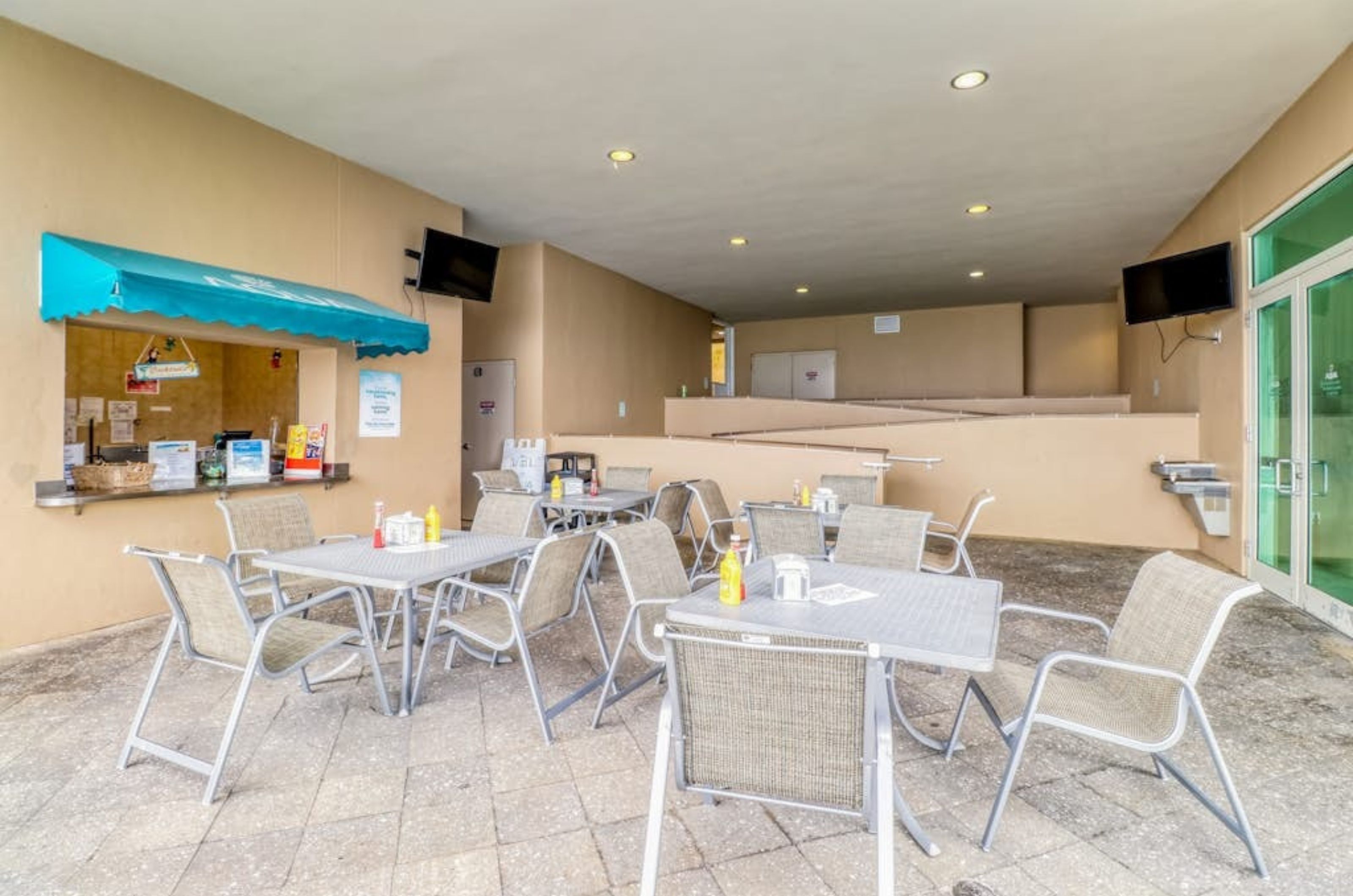 Dining chairs and tables next to the order window at the poolside cafe 