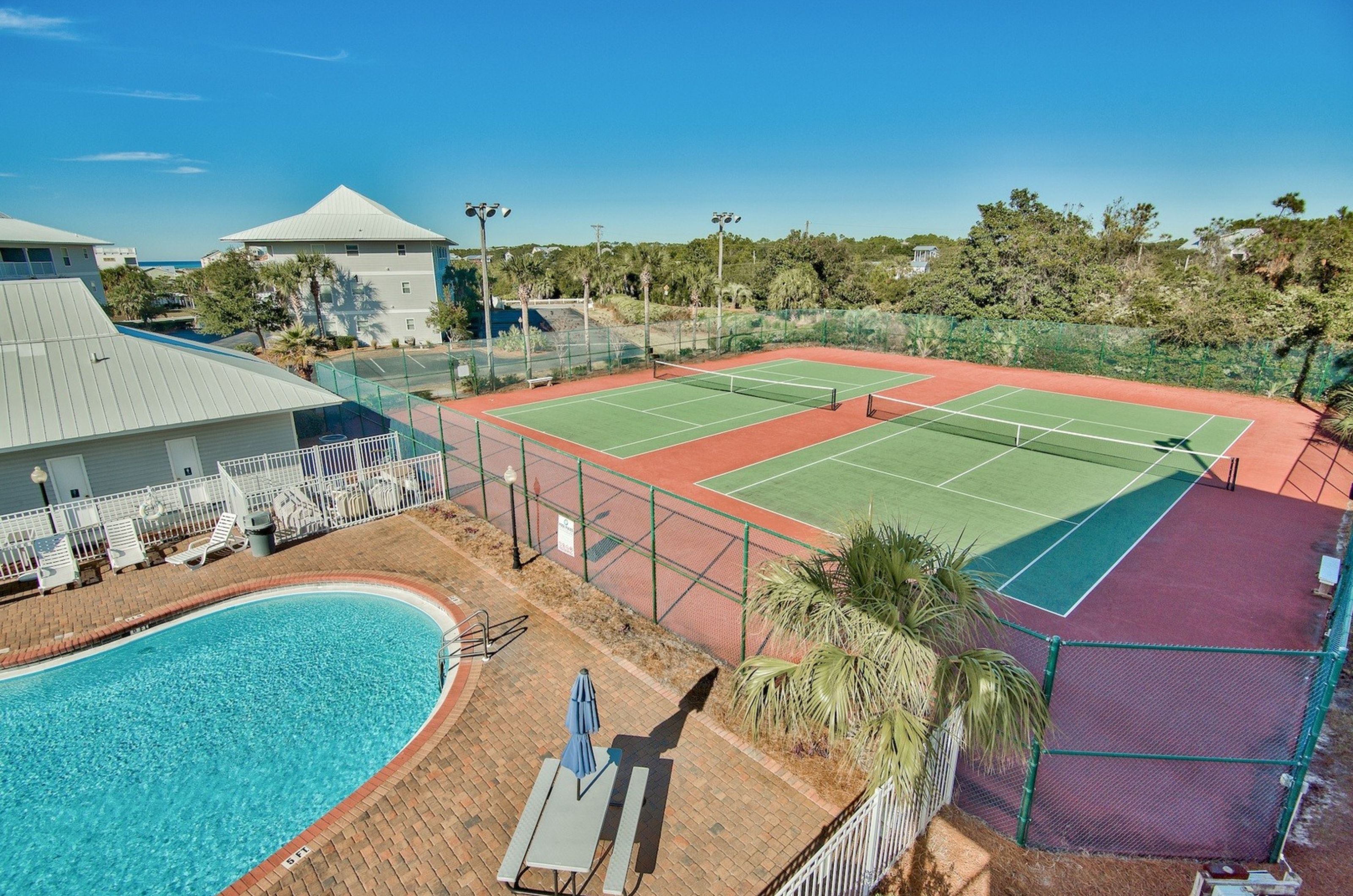 Aerial view of the outdoor tennis courts next to the clubhouse and swimming pool at Beachside Villas