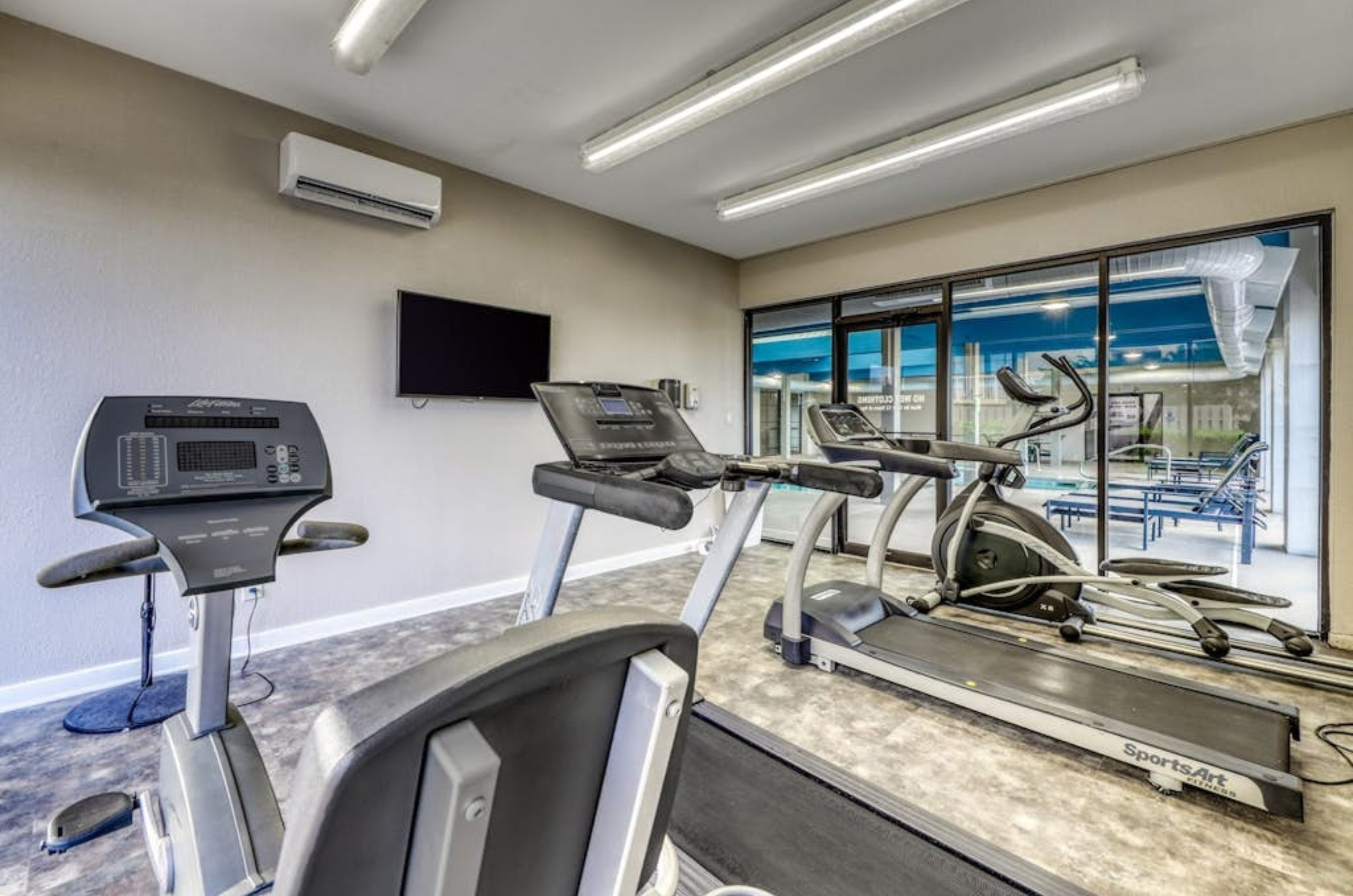 Cardio equpiment and a television in the on-site fitness center at Bluewater Condominiums