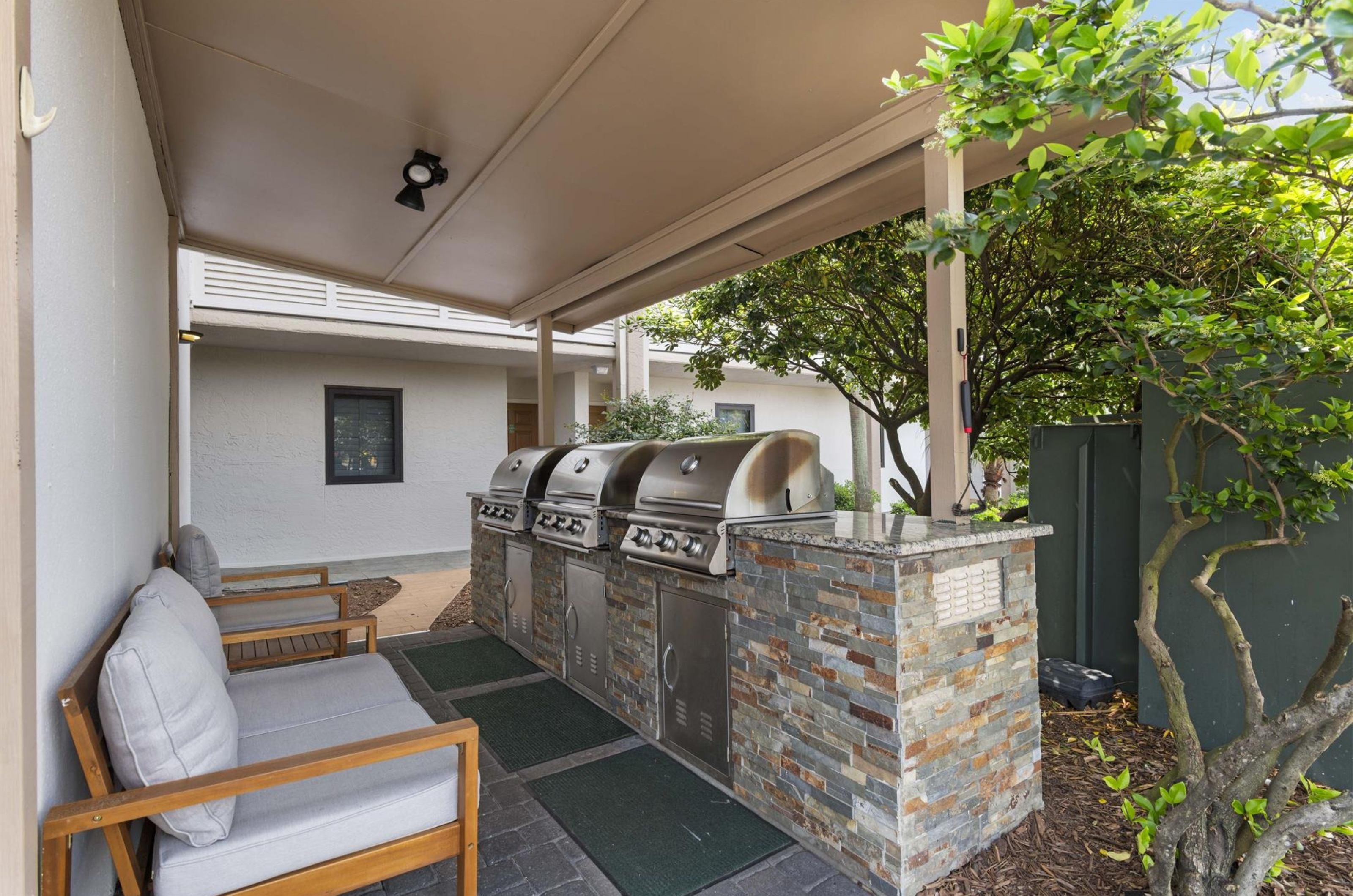 Outdoor grills next to chairs on a covered patio at Destin Beach Club	