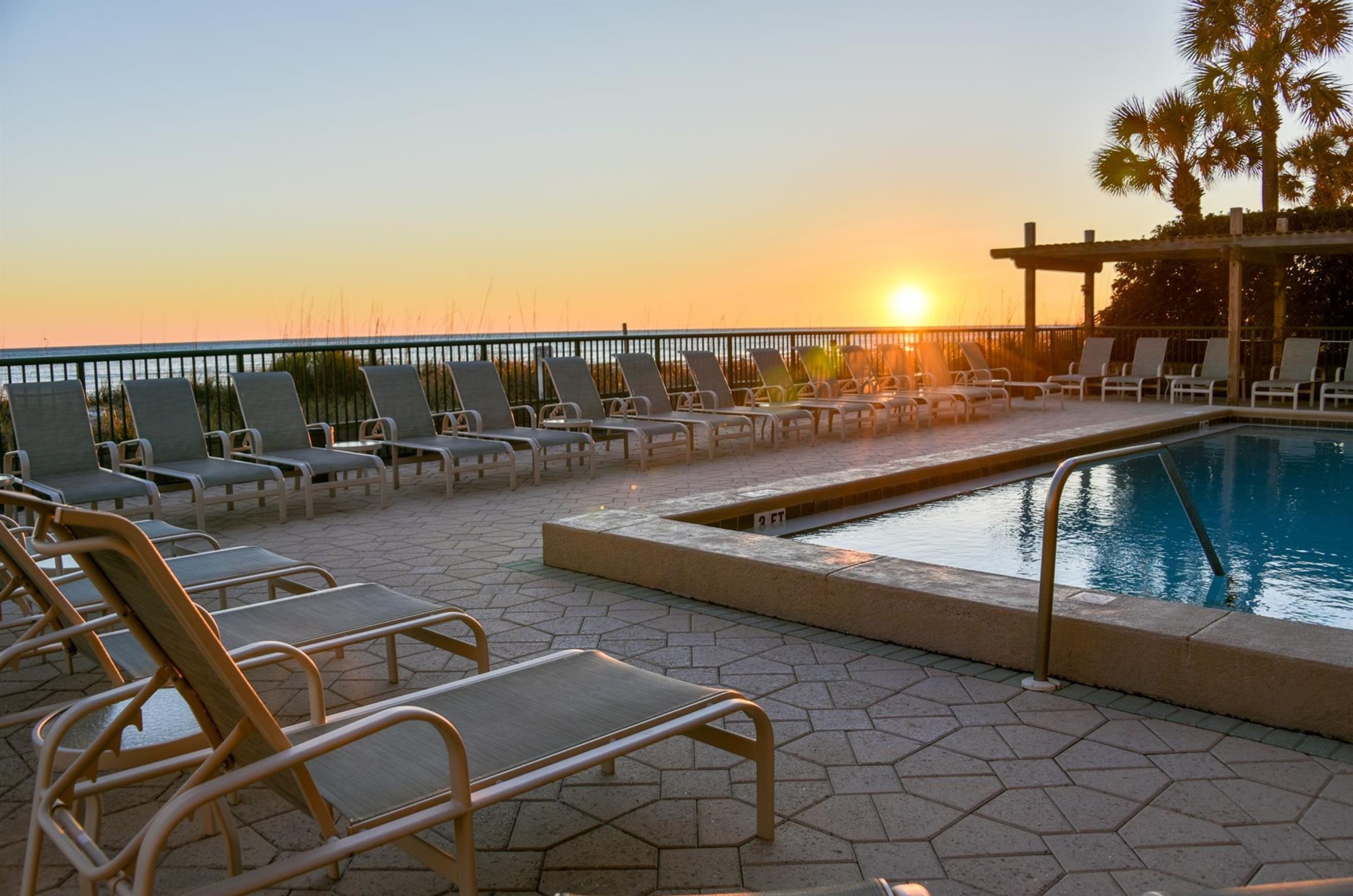 A lounge chair next to the pool at sunset at Destin Beach Club 