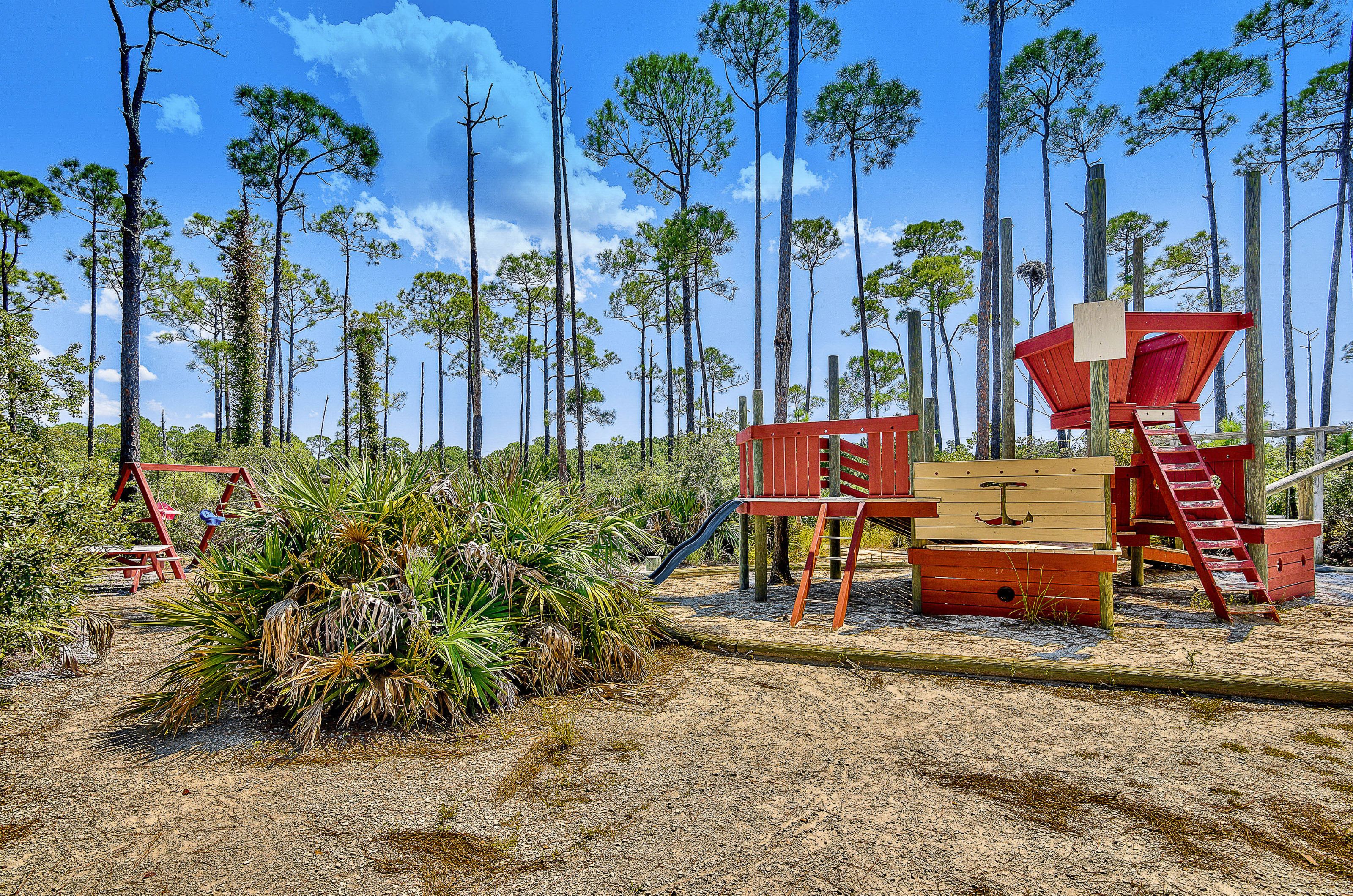 A playground with a swingset slide picnic table and more amid tropical landscaping ready for children and tots to play