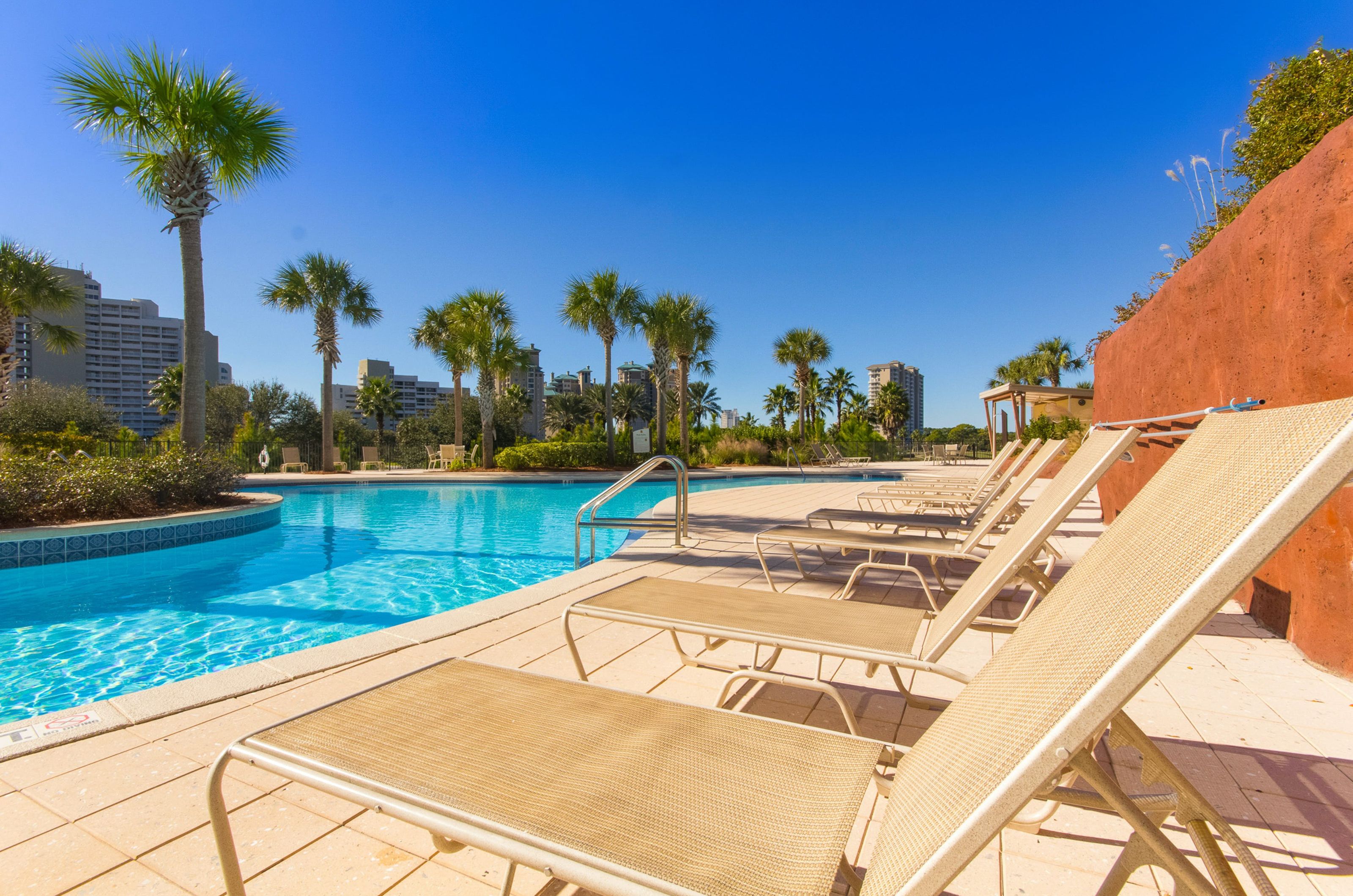 The lagoon pool and spacious sundeck dotted with towering palm trees and ample seating and loungers for guests 