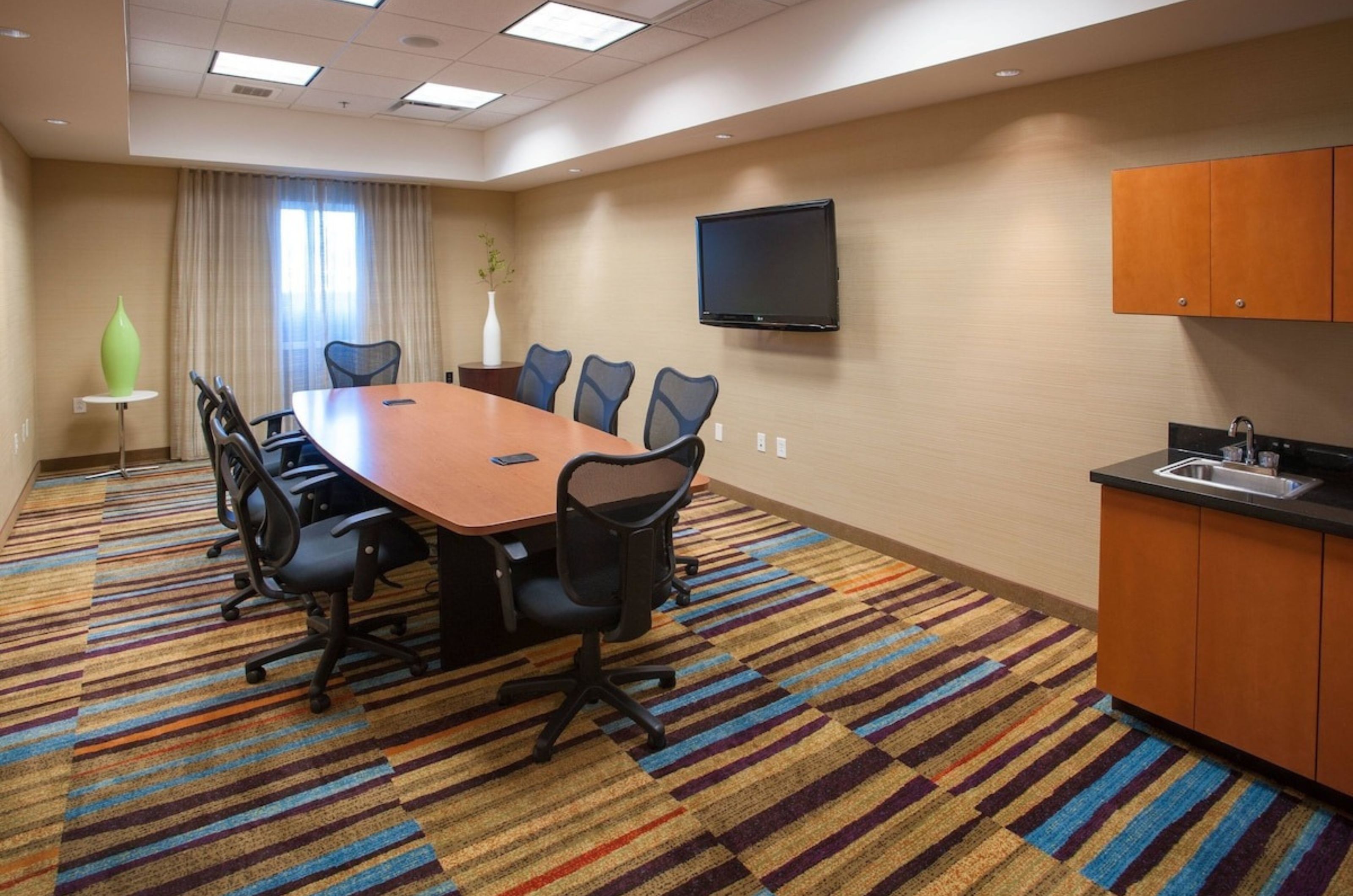 A conference table surrounded by chairs with a TV behind the table at Fairfield Inn and Suites in Orange Beach Alabama 