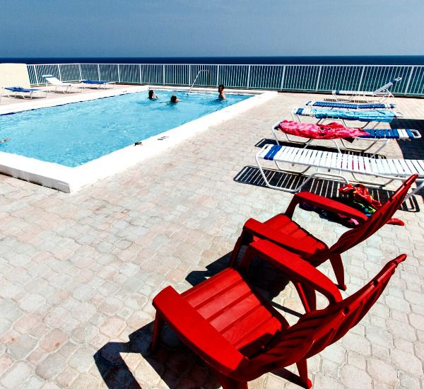 Coloful beach chairs and loungers line the poolside sundeck at Gulfside Condo Fort Walton Beach.