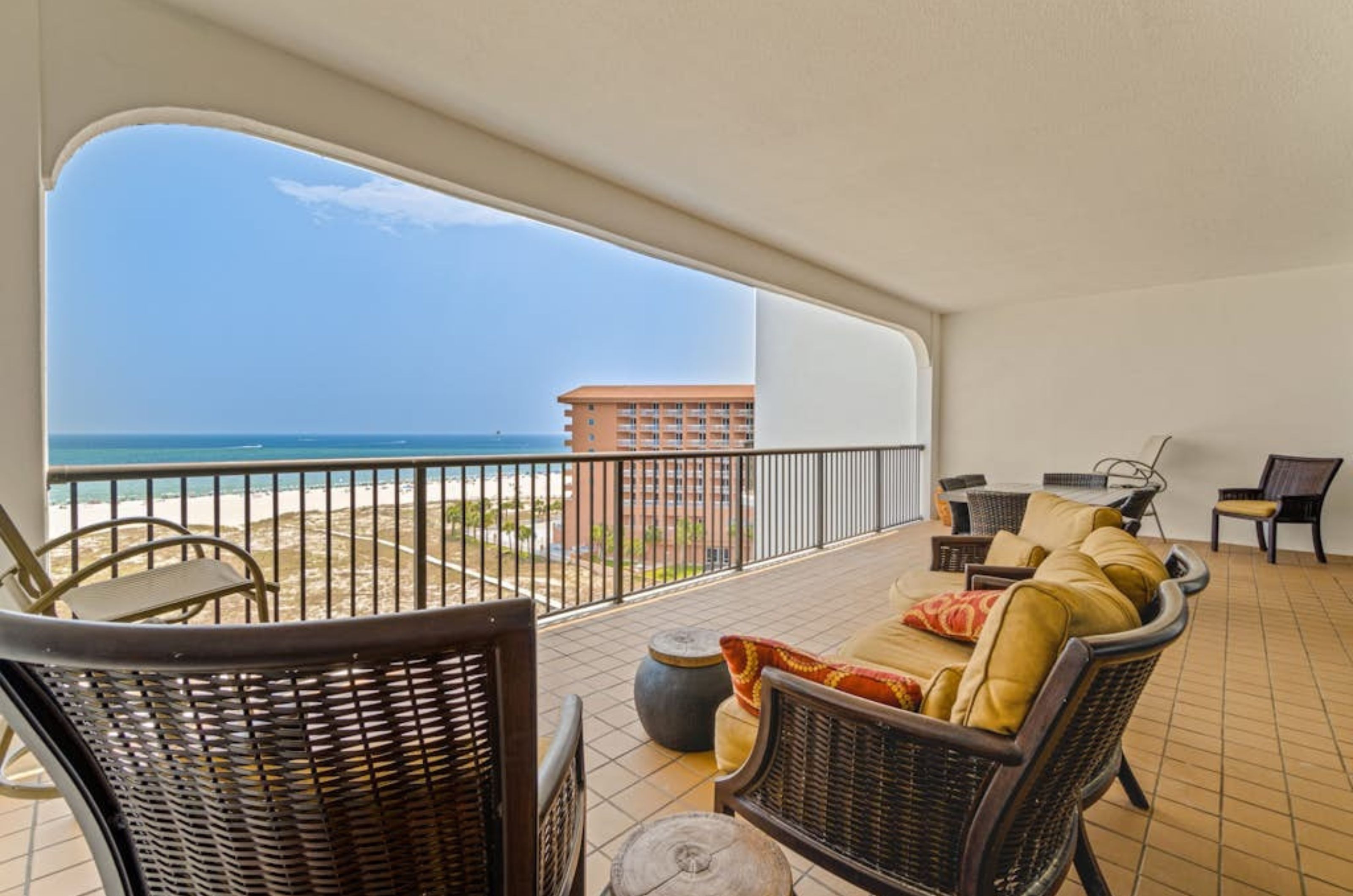 A large balcony with multiple chairs and tables at Grand Pointe in Orange Beach Alabama	