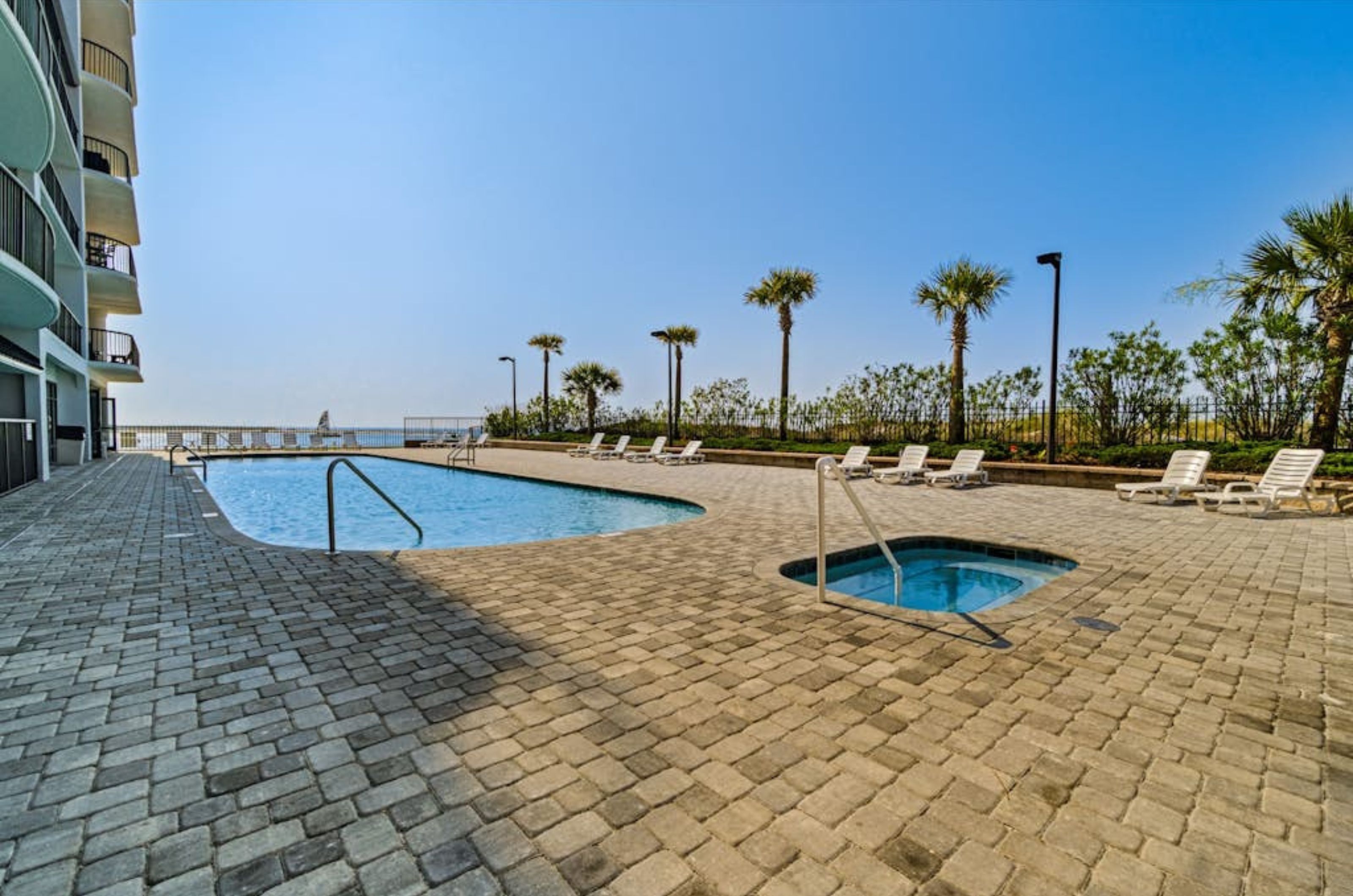 The outdoor pool and hot tub surrounded by lounge chairs at Grand Point in Orange Beach Alabama 