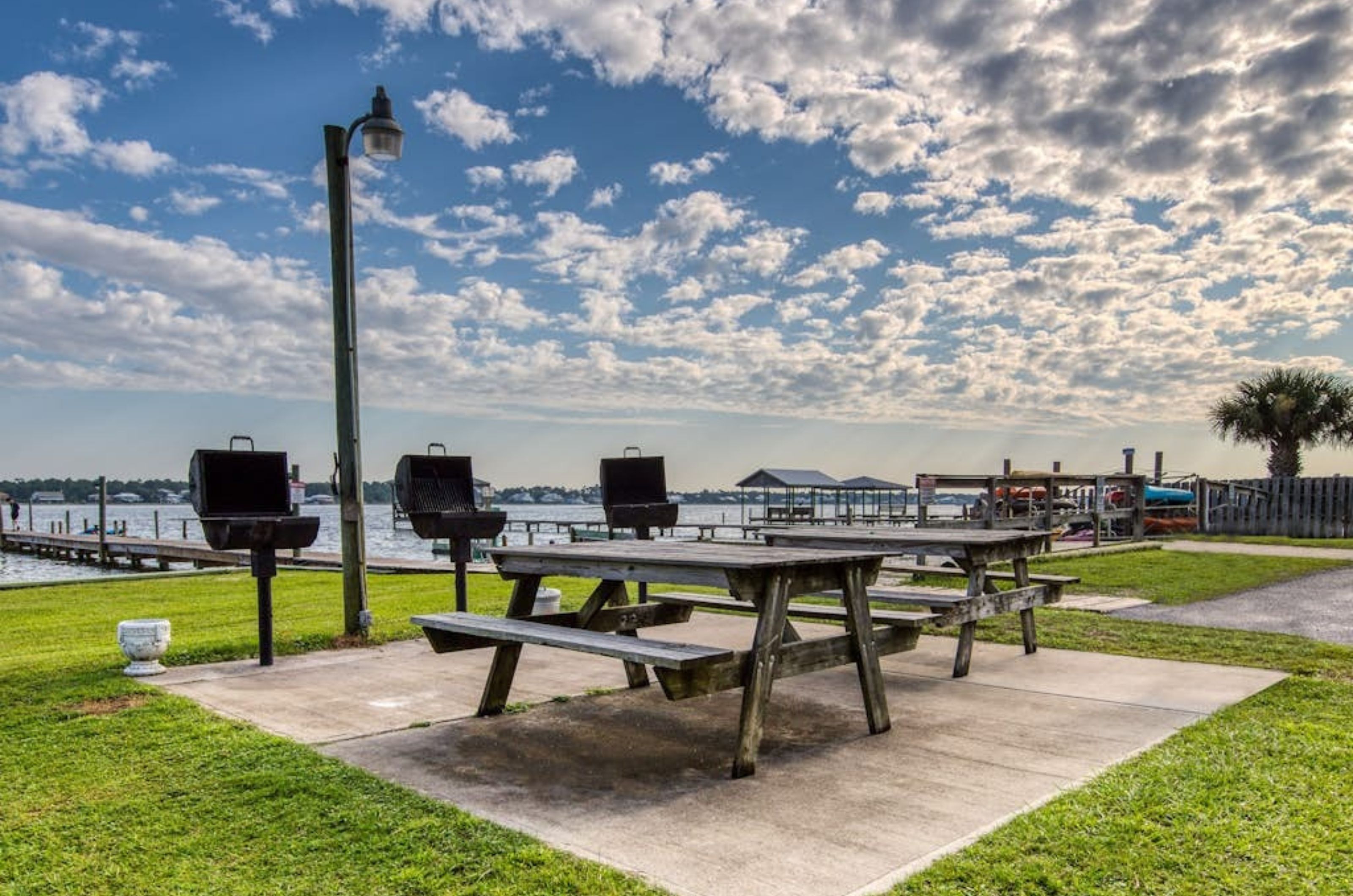 Barbecue grills and a wooden picnic table next to the lagoon at Gulf Shores Surf and Racquet Club