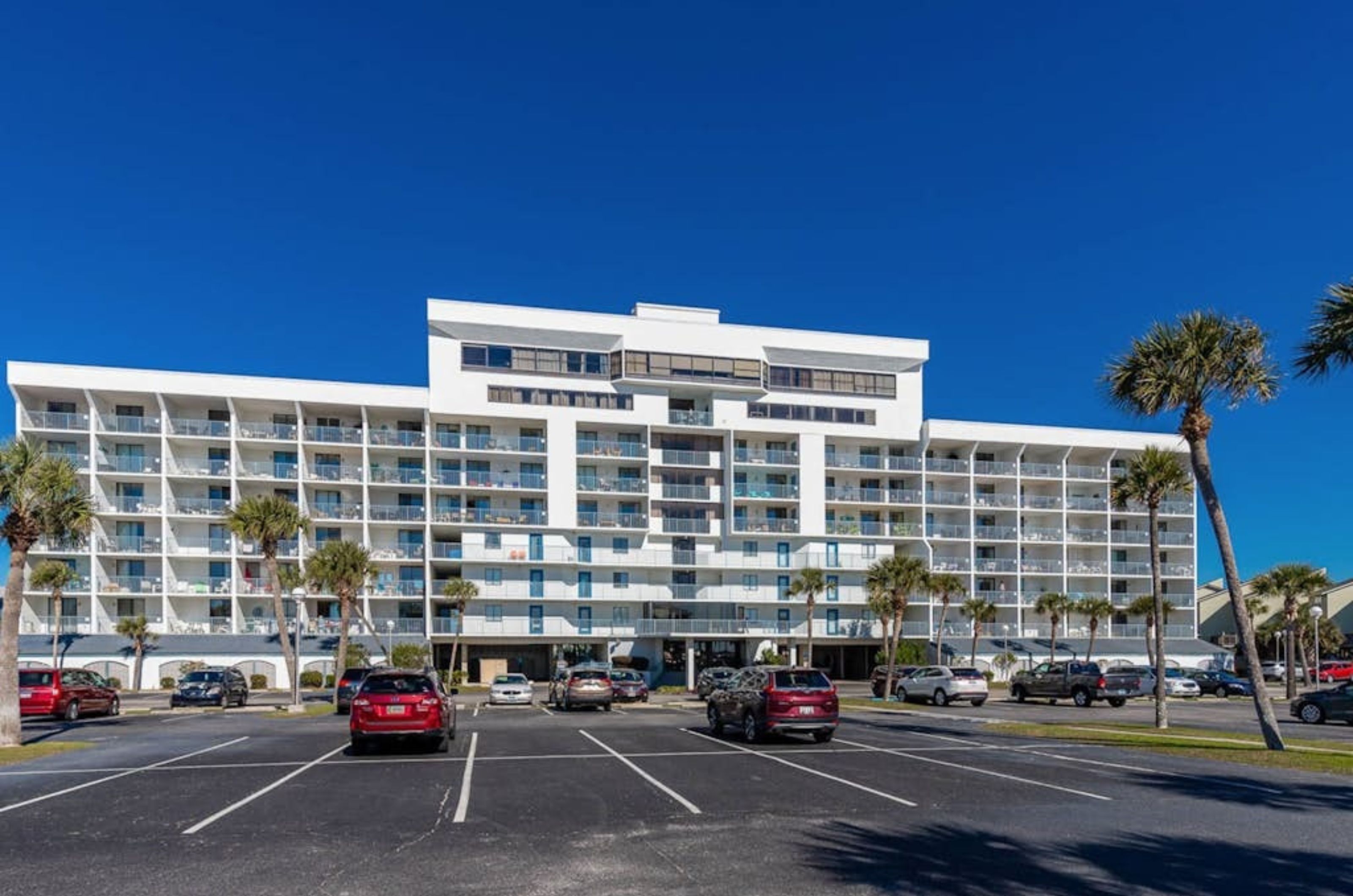 Gulf Shores Surf and Racquet Club with cars in the parking lot in front of the complex