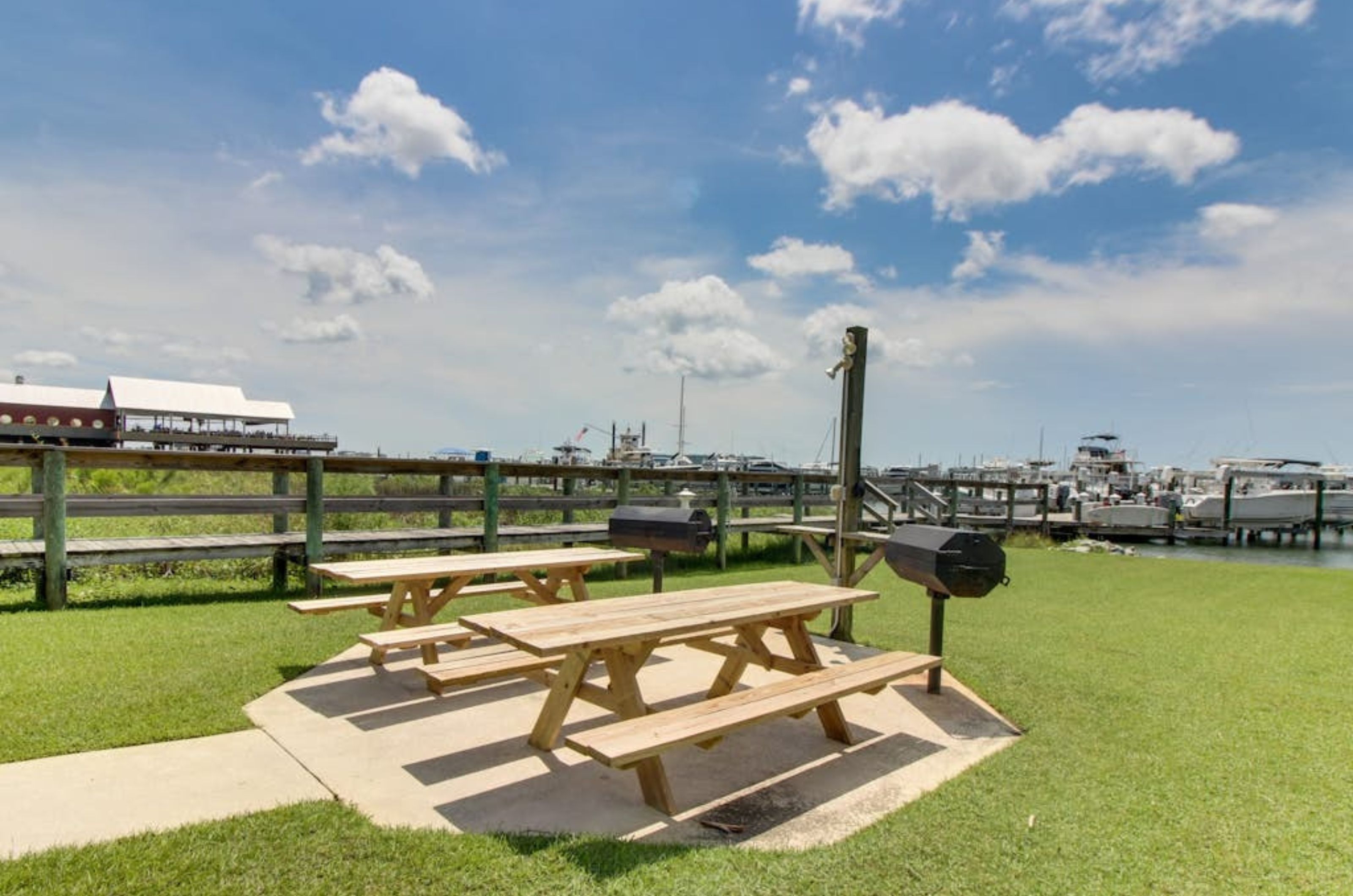 Charcoal grills next to wooden picnic tables at Harbor Cove in Orange Beach Alabama