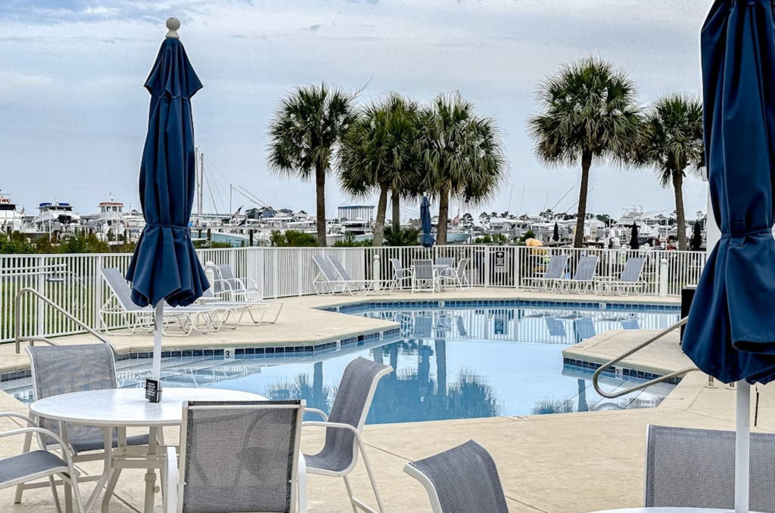 The outdoor pool and pool deck with chairs and tables at Harbor Cove