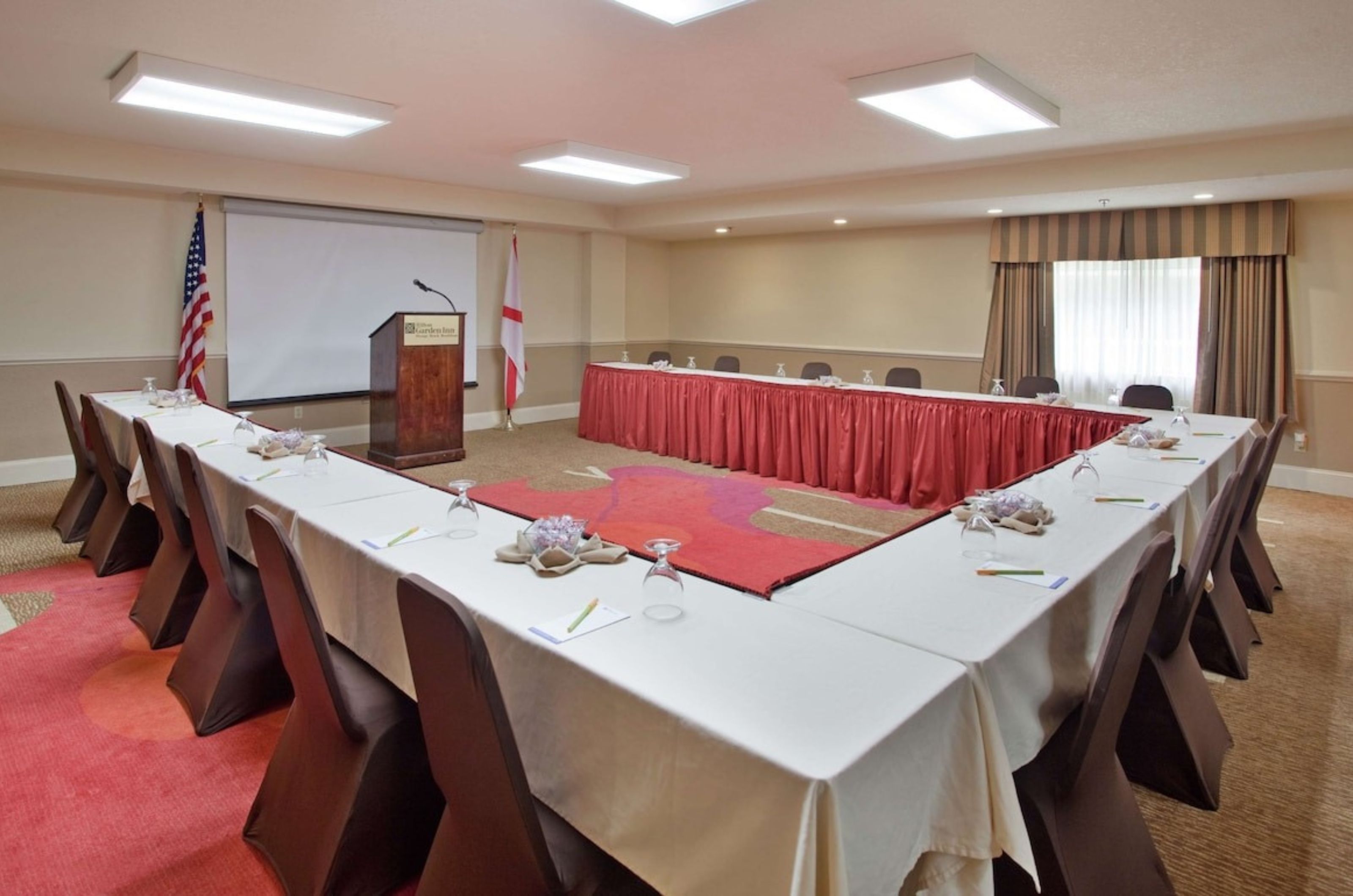 A meeting room with a podium and u-shaped table at Hilton Garden Inn 