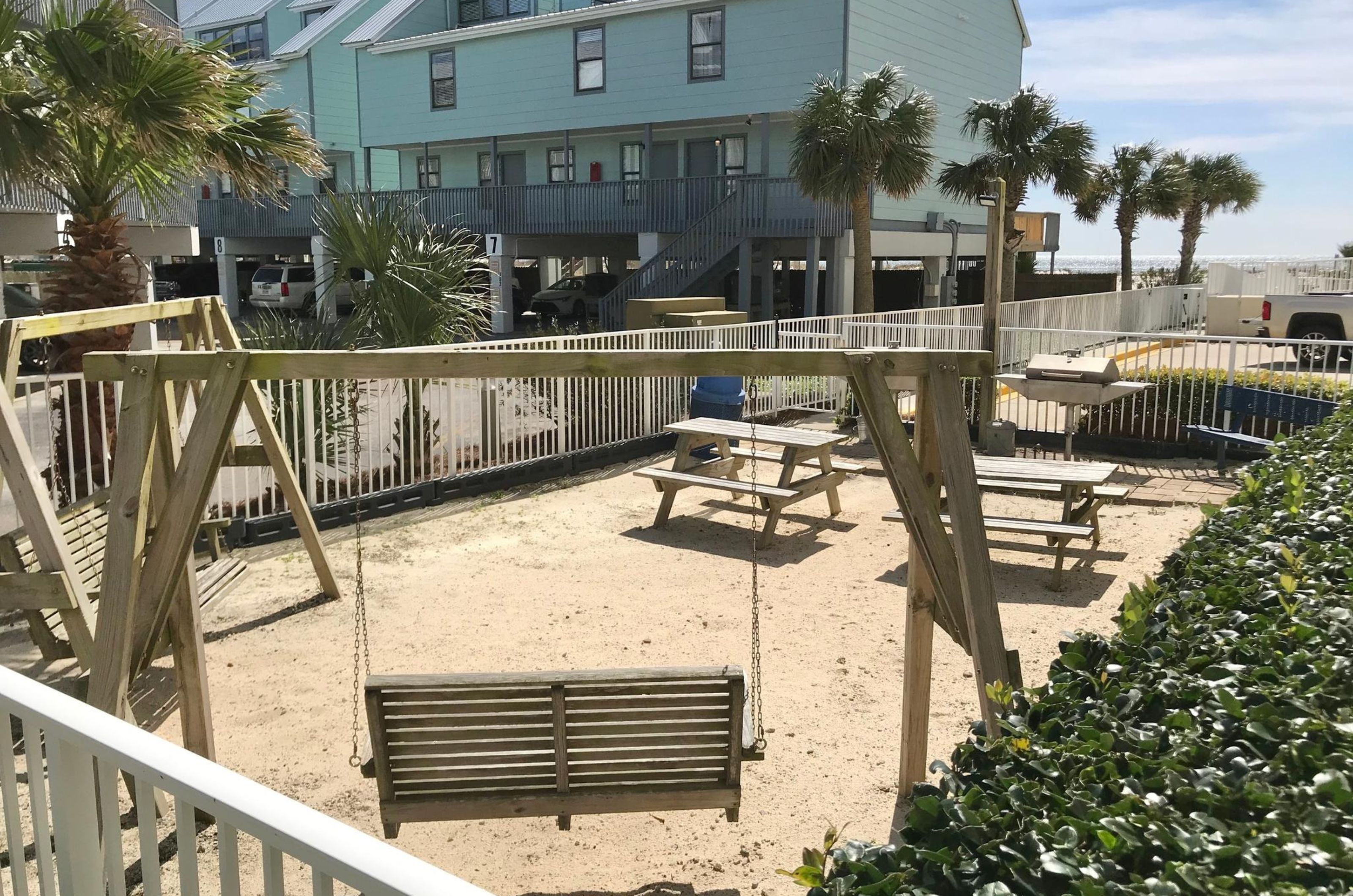 A wooden porch swing and picnic table next to the outdoor barbecue grills at Island Tower 