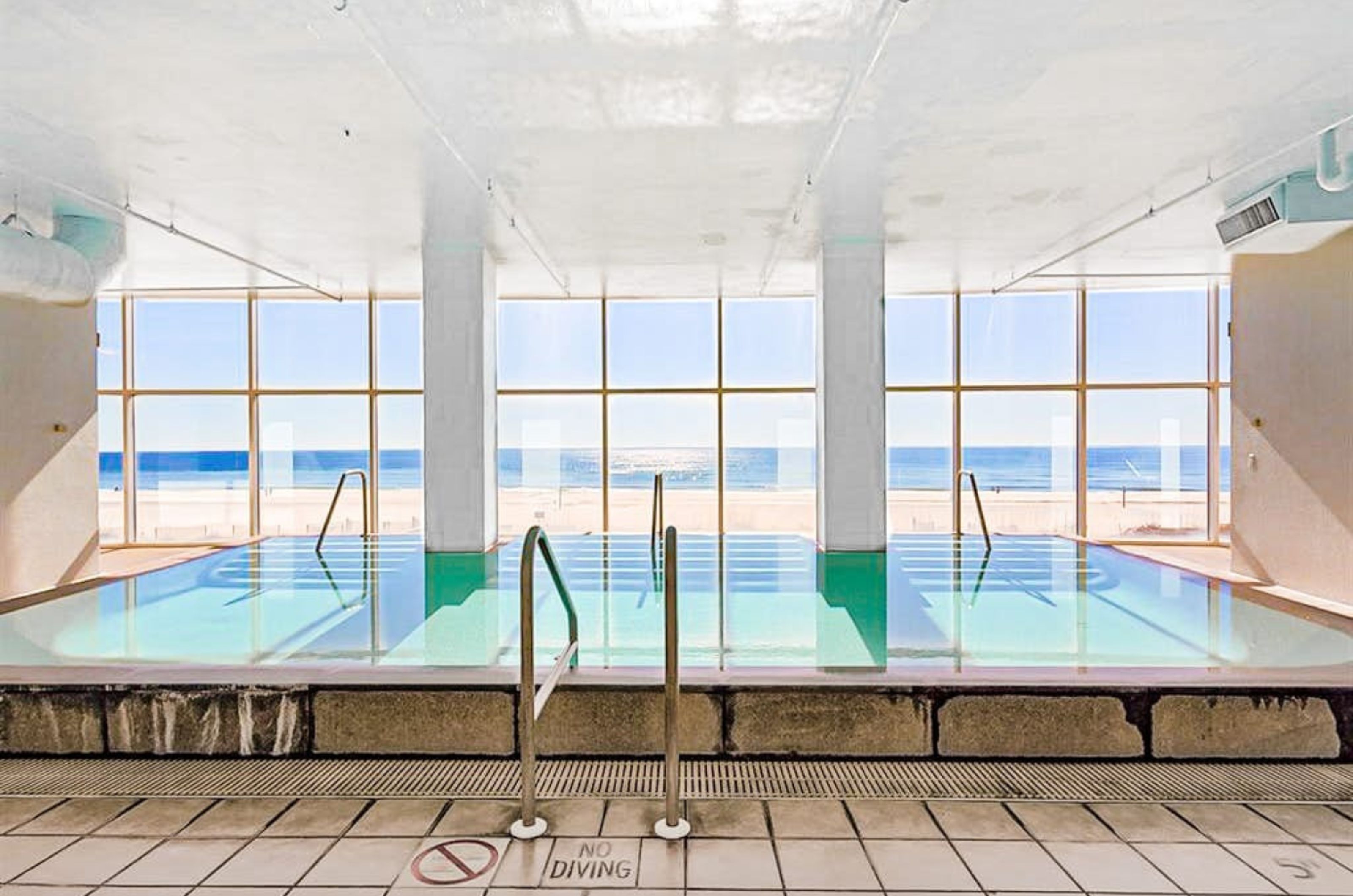 The indoor swimming pool next to floor to ceiling windows overlooking the beach at Island Tower 