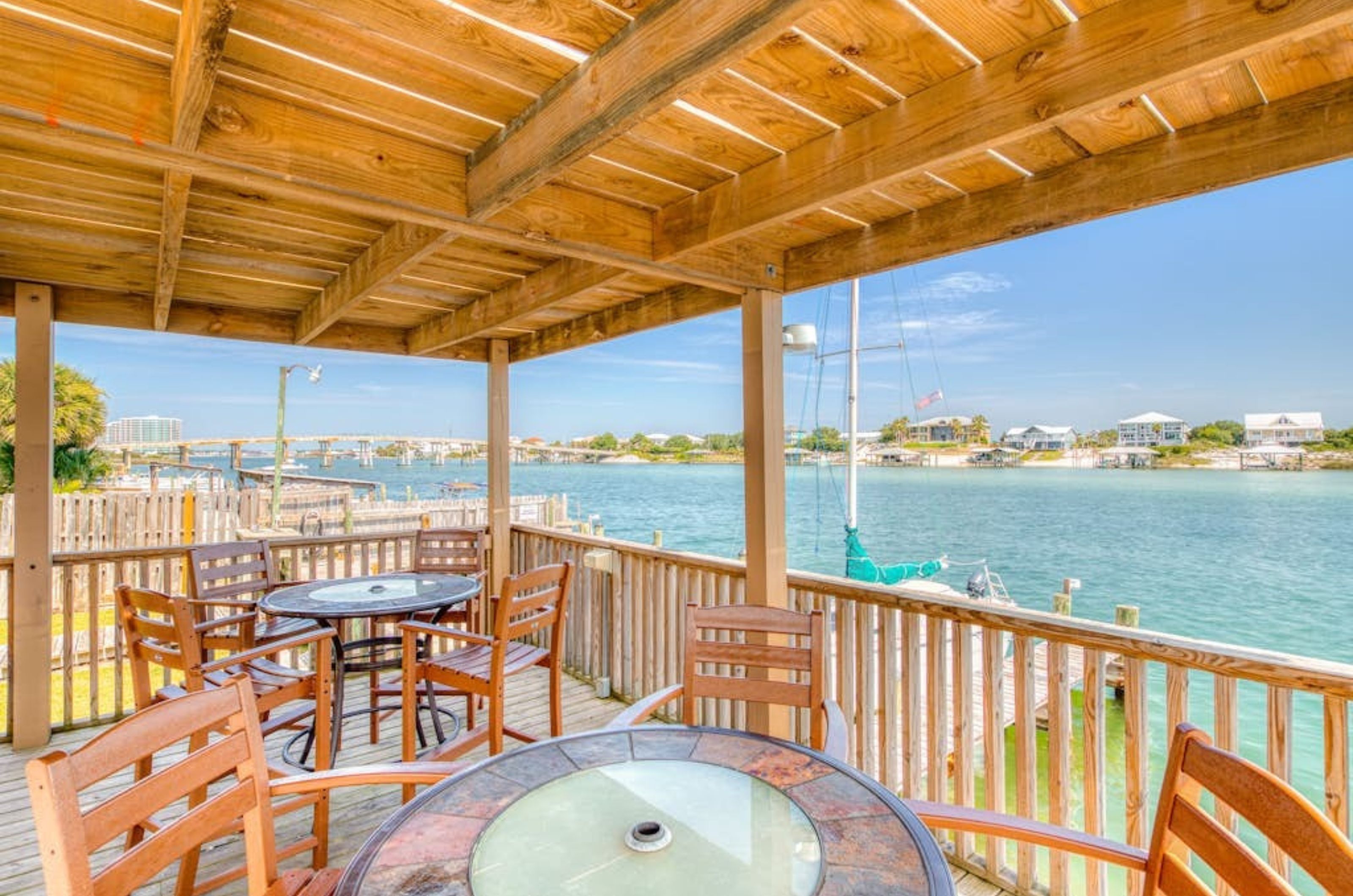 Tables and chairs on a wooden terrace next to the bay at Lei Lani 