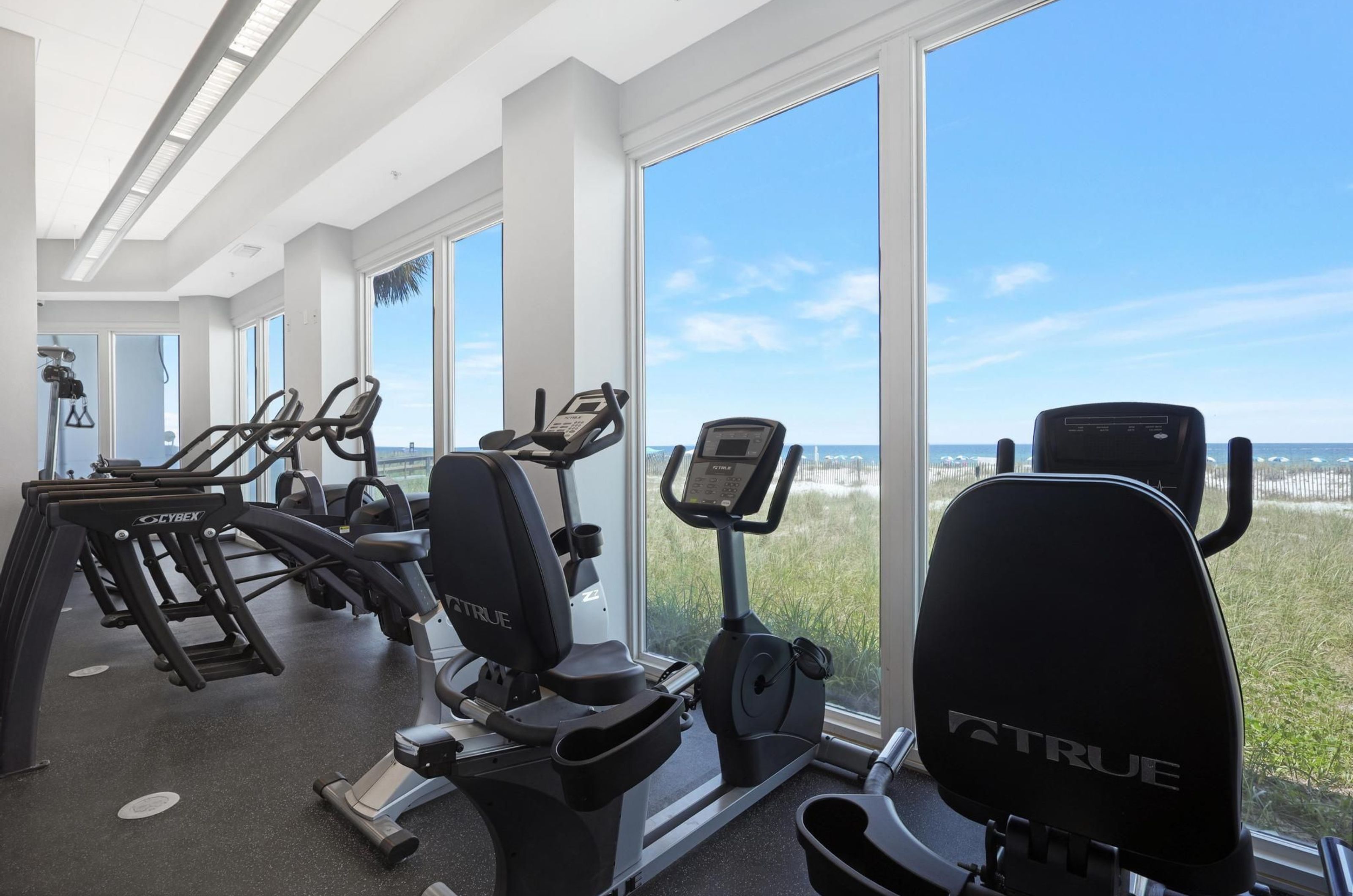 Cardio equipment next to windows facing the beach  