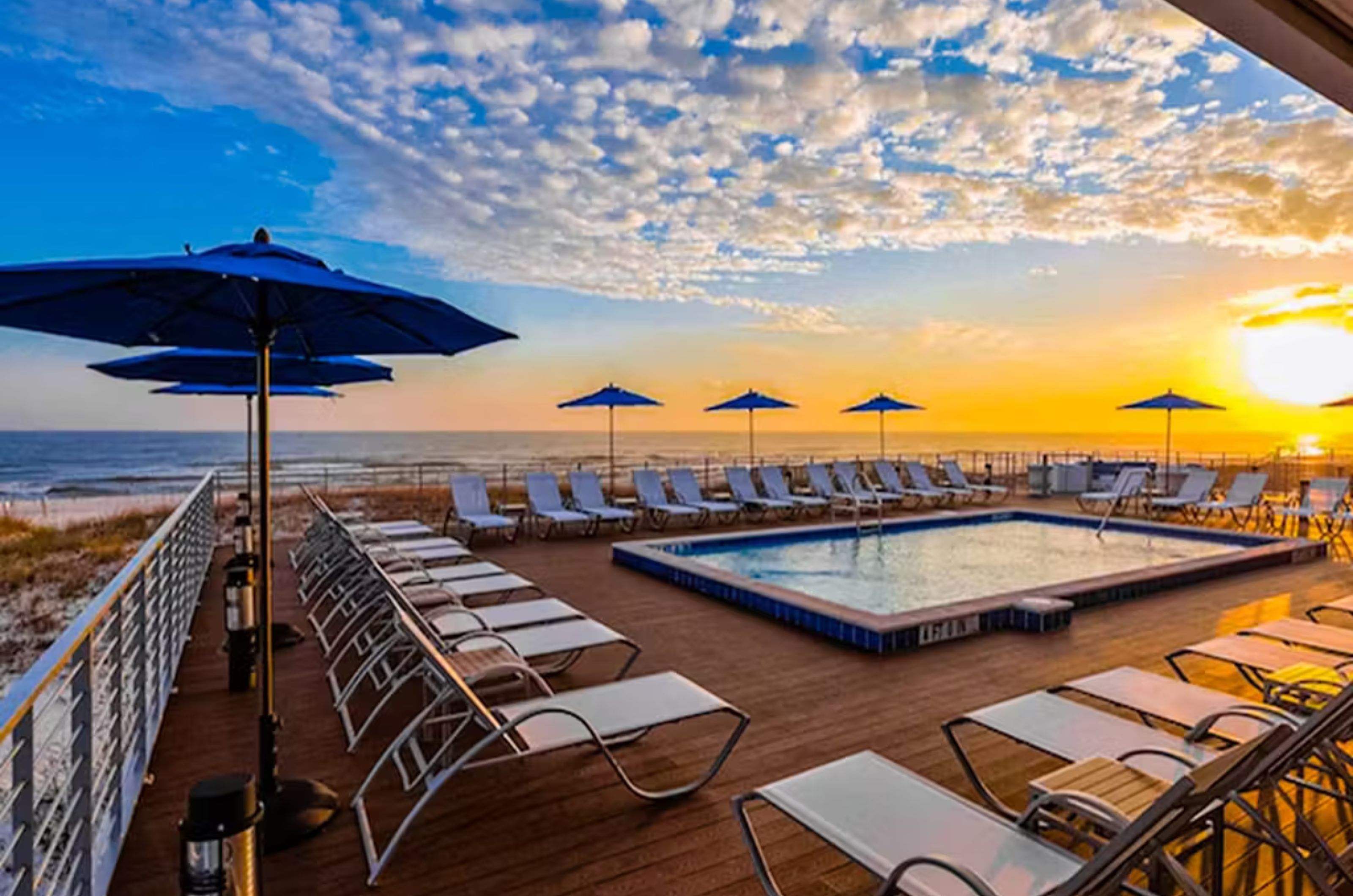 A sparkling pool and lounge chairs overlooking the Gulf at sunset 