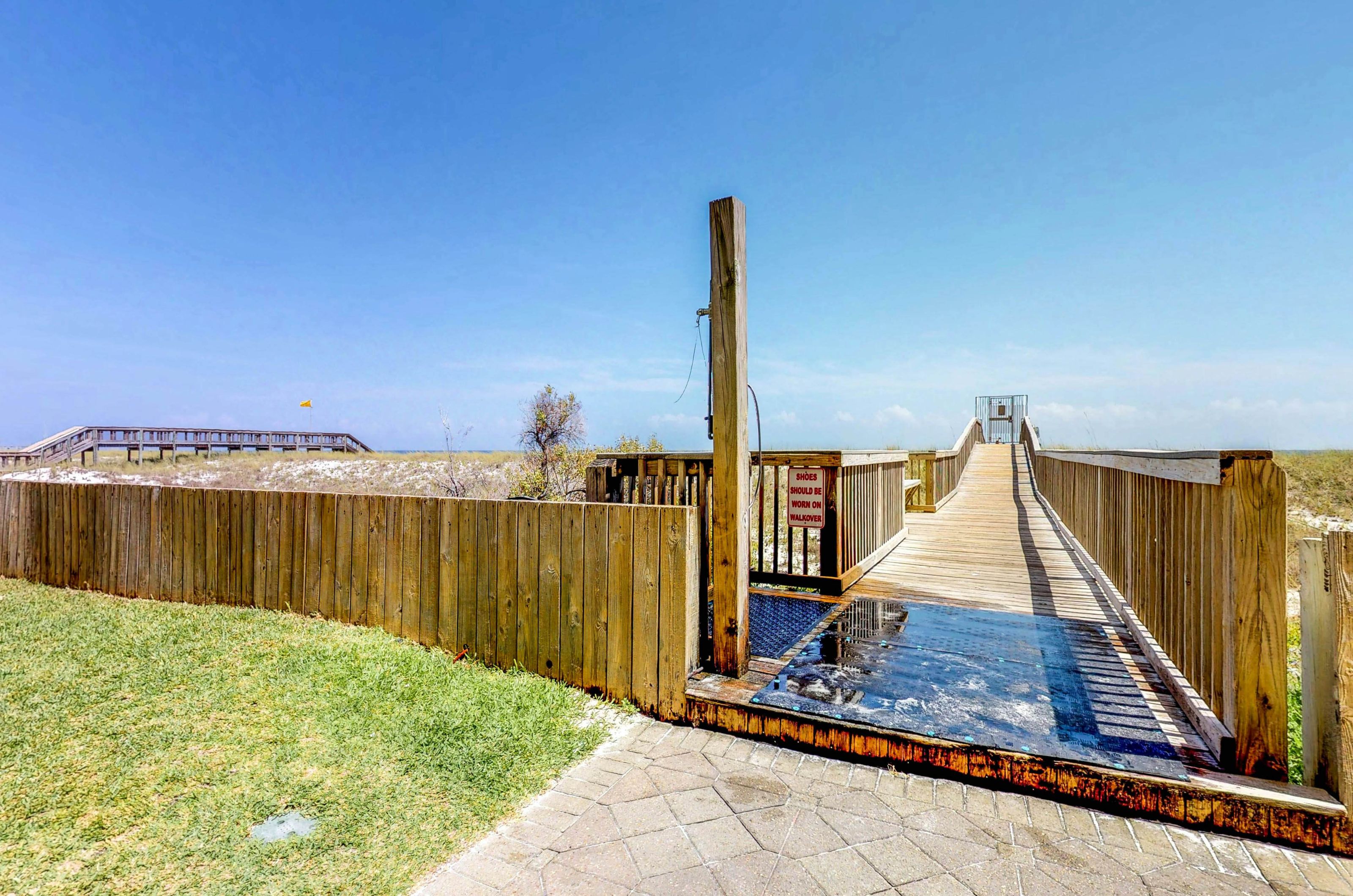 Gated boardwalk to the beach and outdoor shower at the entrance 