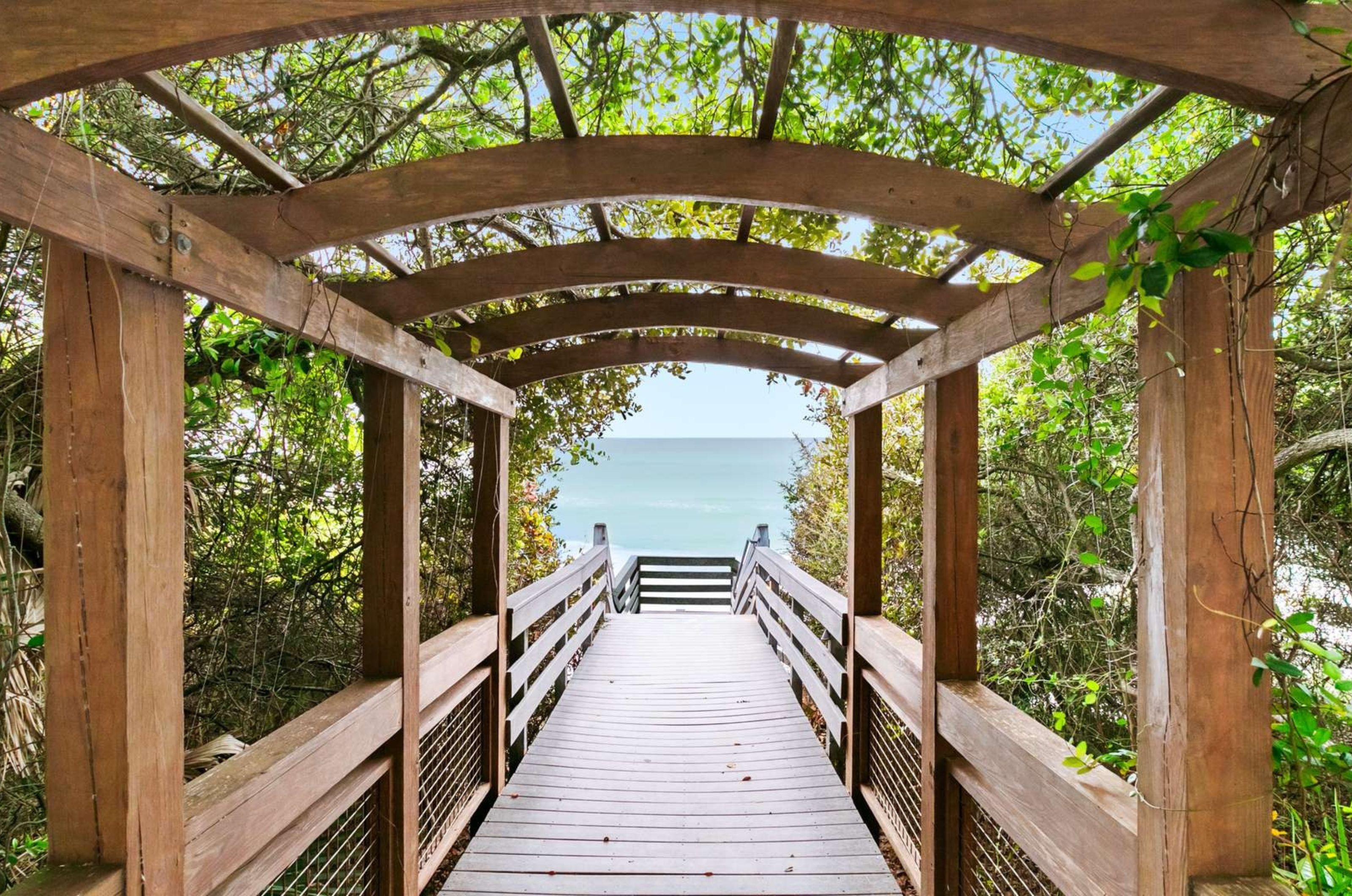 A wooden boardwalk leading to the Gulf in front of One Seagrove Place 