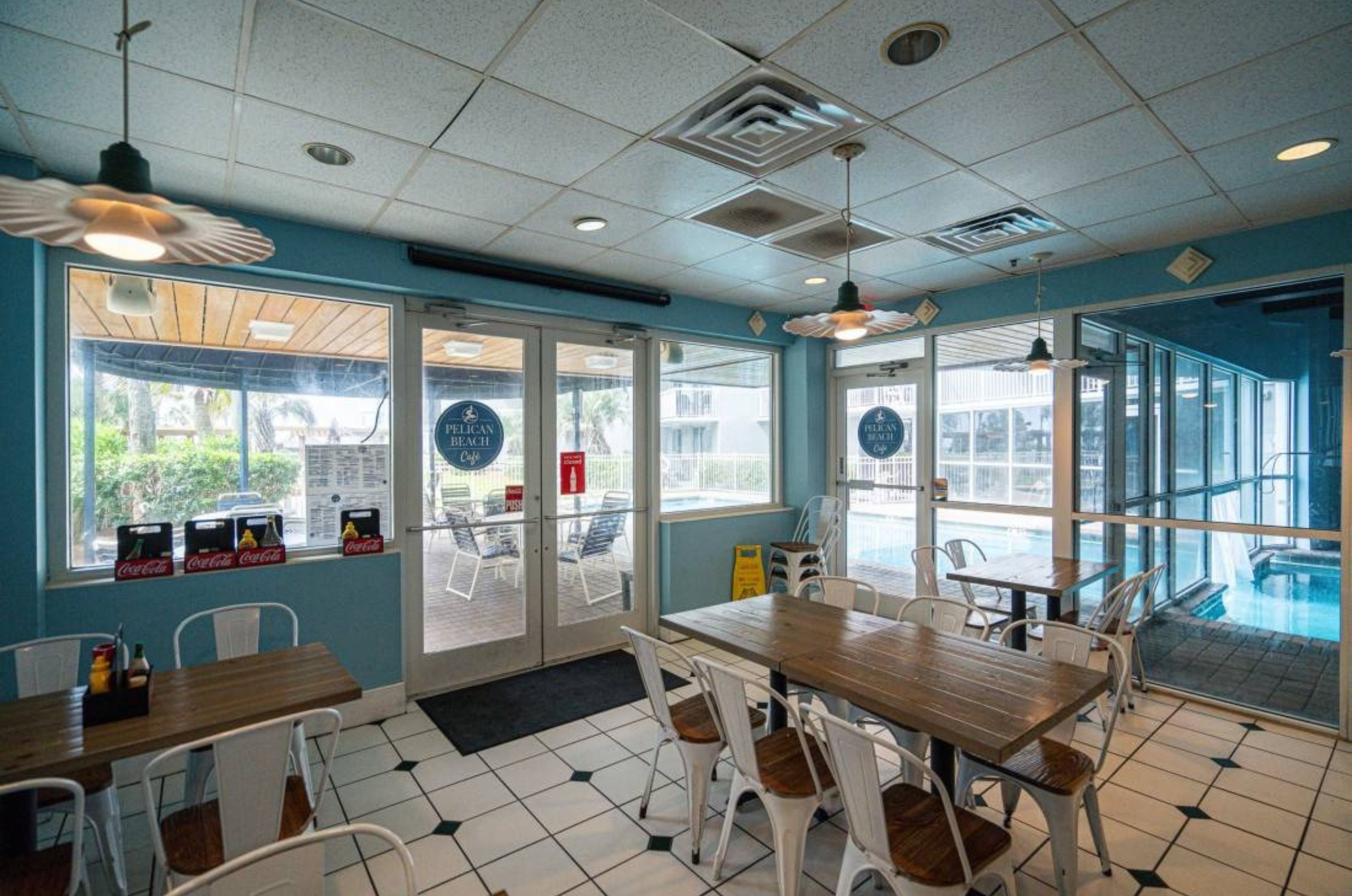 The front of the cafe with dining tables and chairs at Pelican Beach Resort