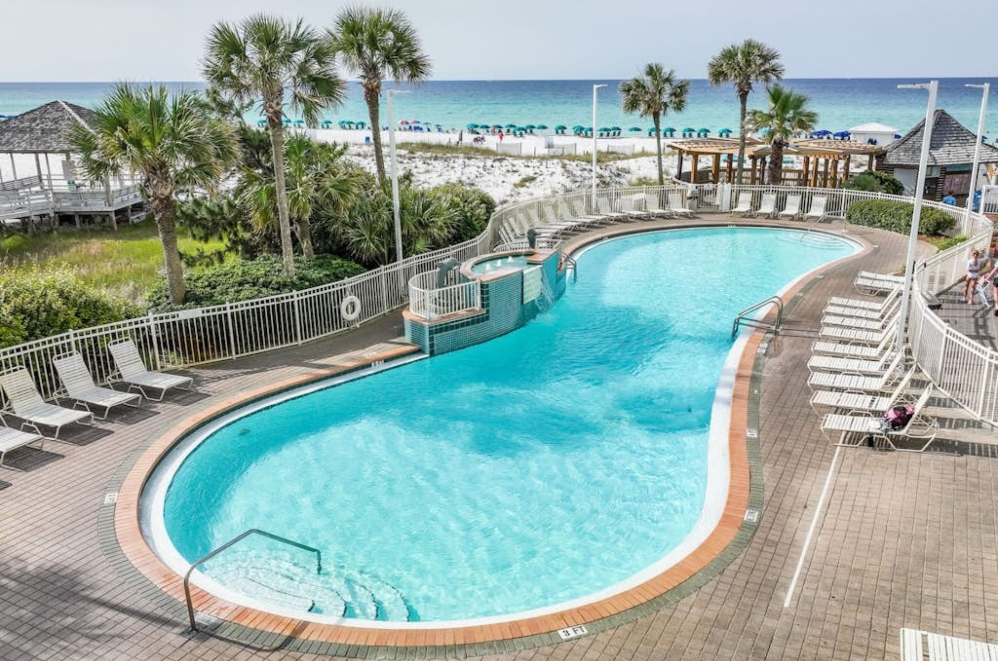 An outdoor swimming pool next to the Gulf at Pelican Beach Resort 