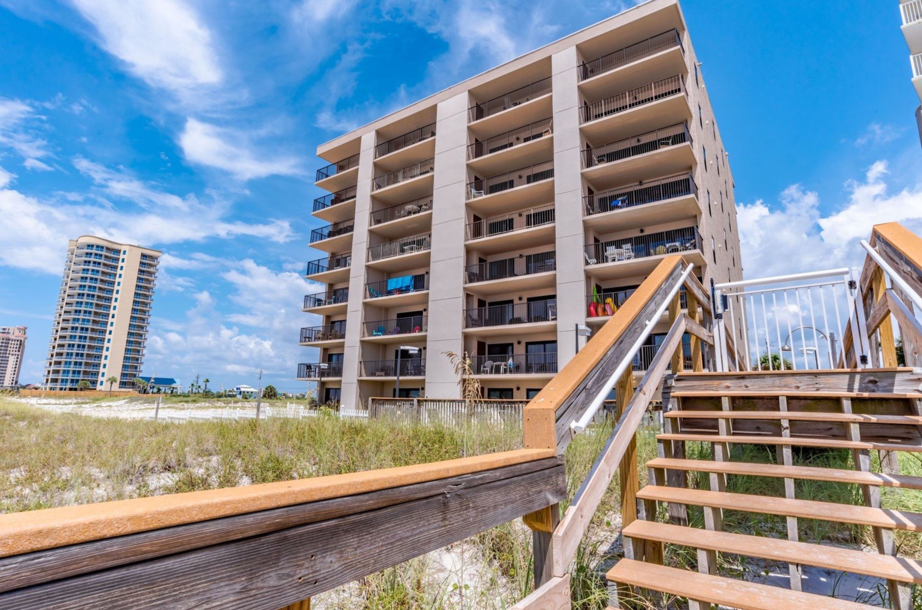 The beachside exterior of Ocean Breeze East with a wooden boardwalk in Perdido Key Florida 