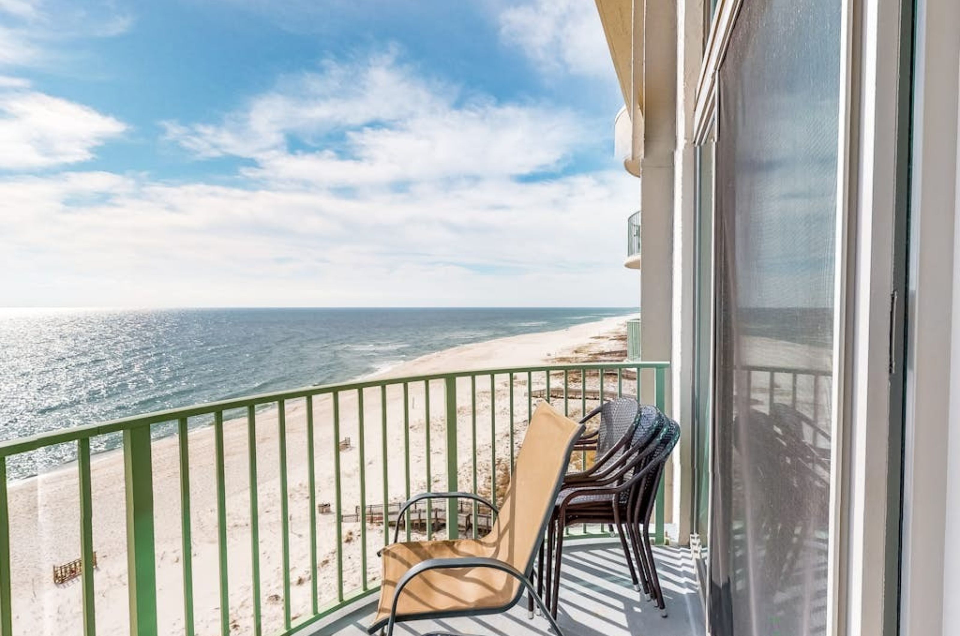 View down the coast from a private balcony with a chair and table 