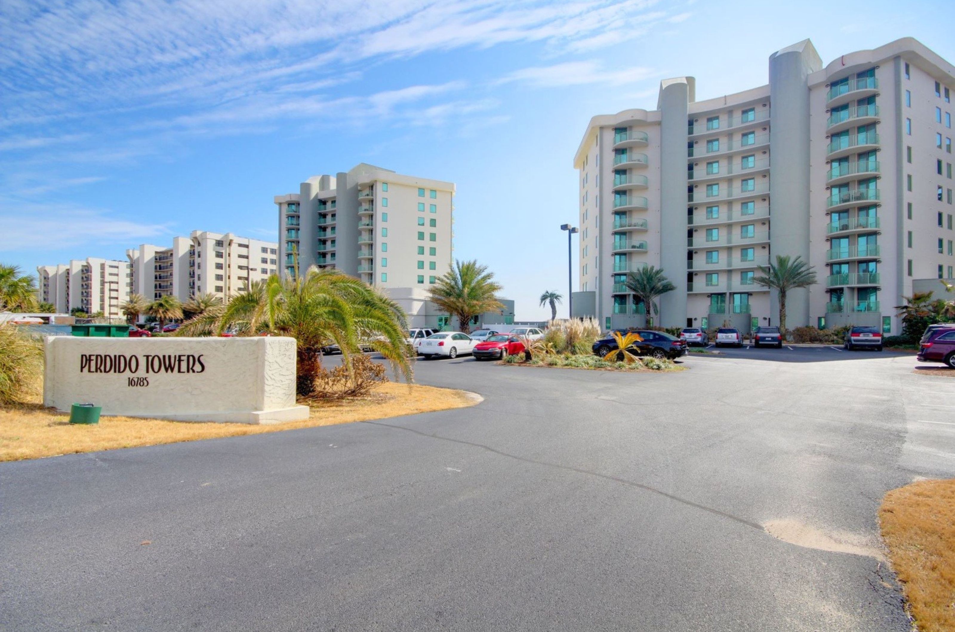 View from the street of Perdido Towers and the property's entry sign and parking lot