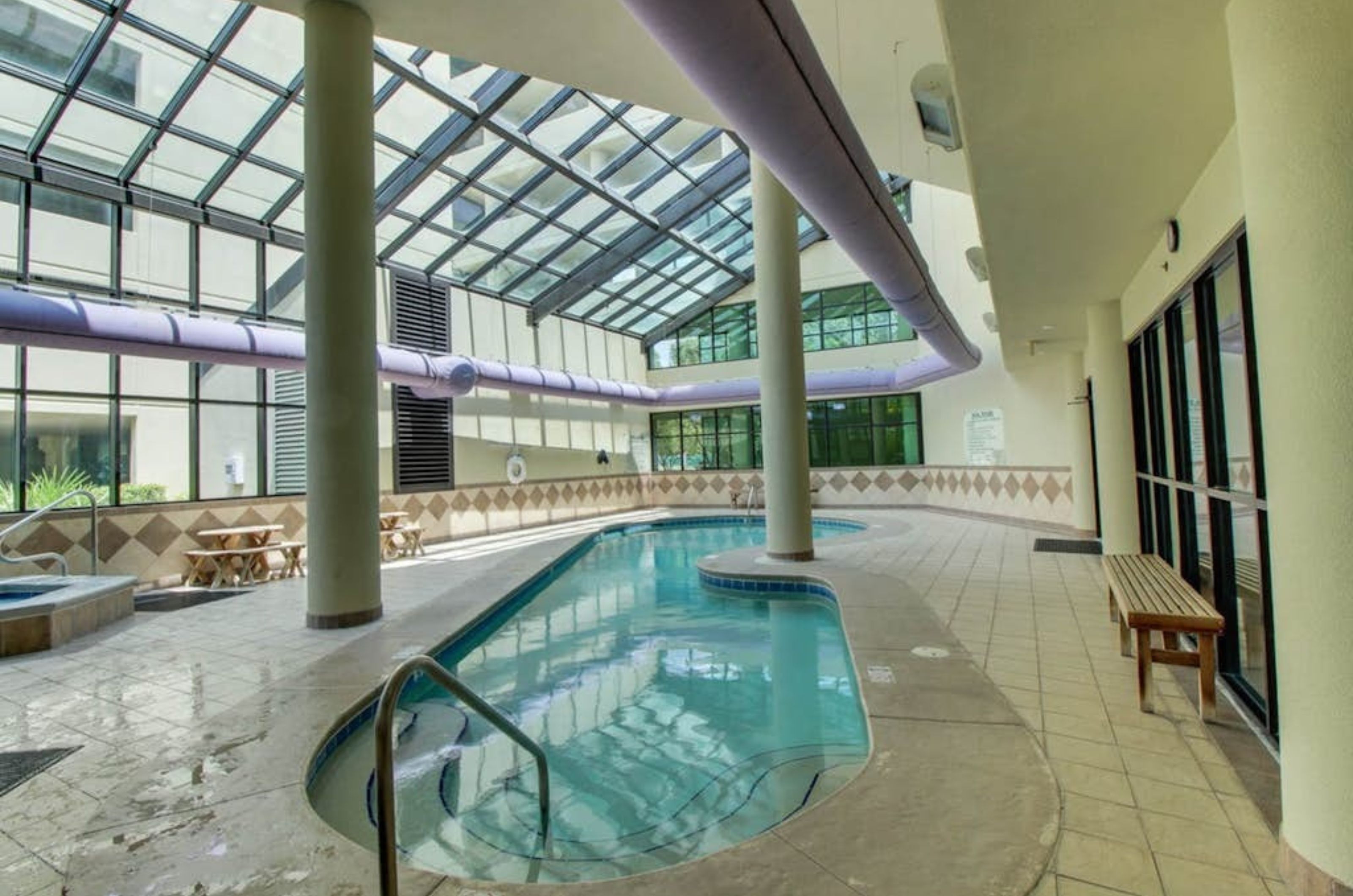 An indoor swimming pool with a spacious pool deck and windows