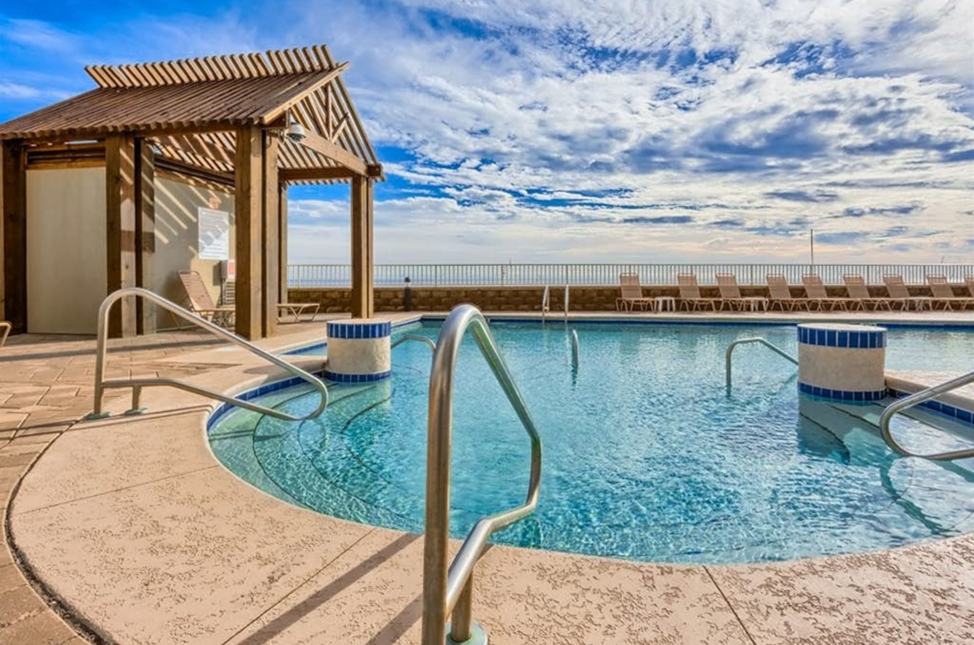 Lounge chairs next to the beachfront swimming pool at Romar Place