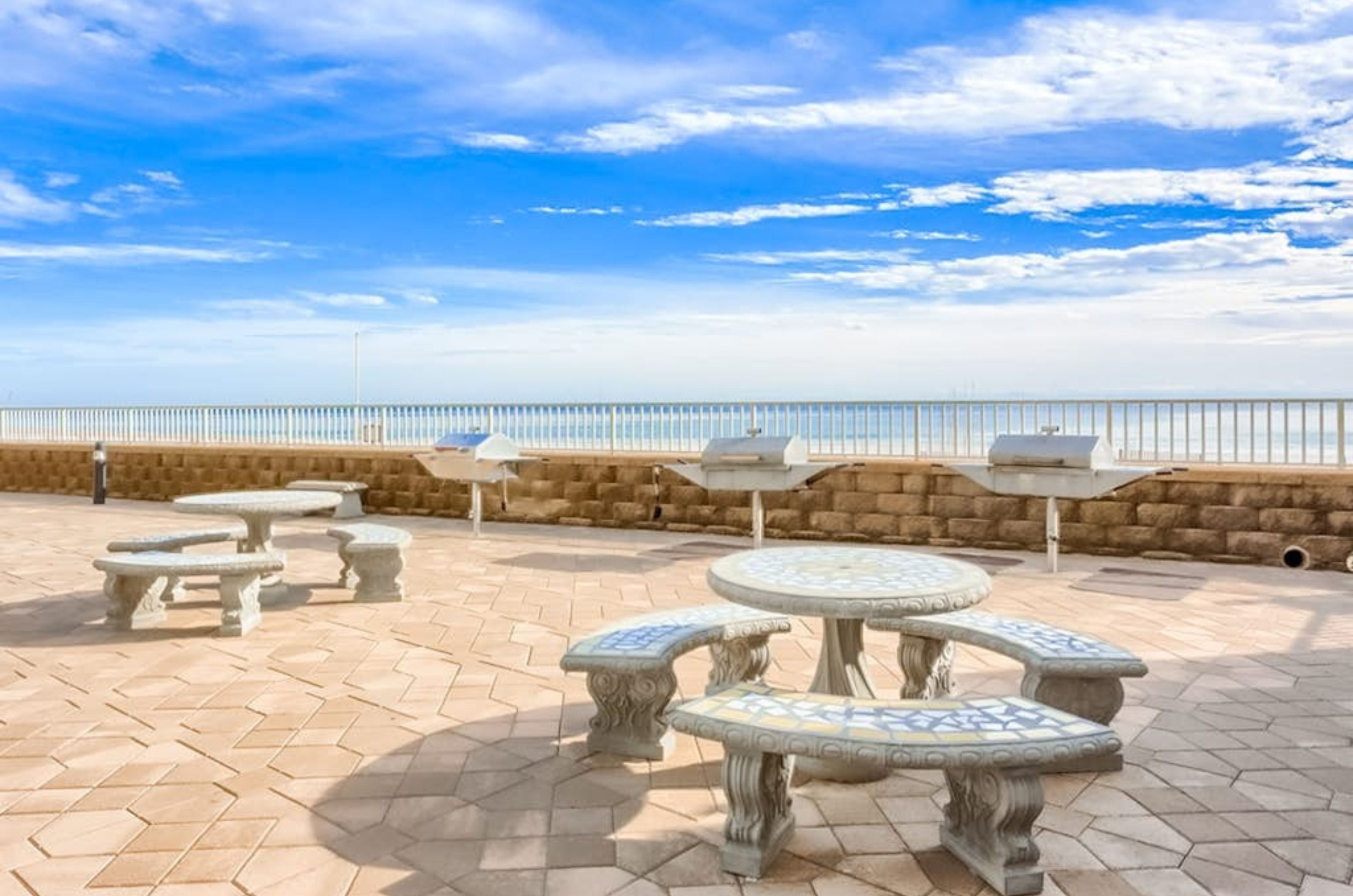 Stone tables and barbecue grills next to the beach at Romar Place