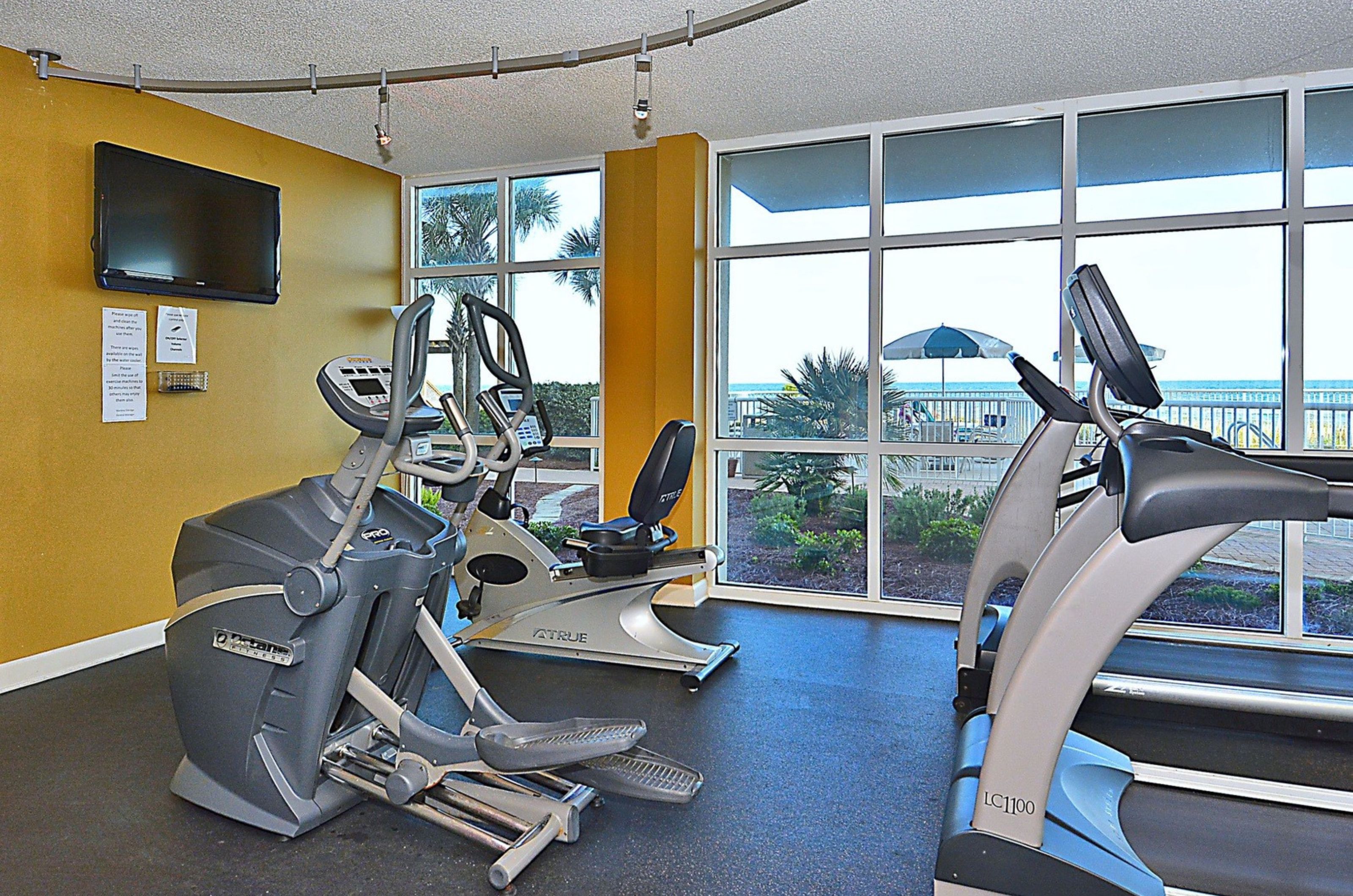 The gym with cardio equipment next to windows at Sandy Key Condominiums