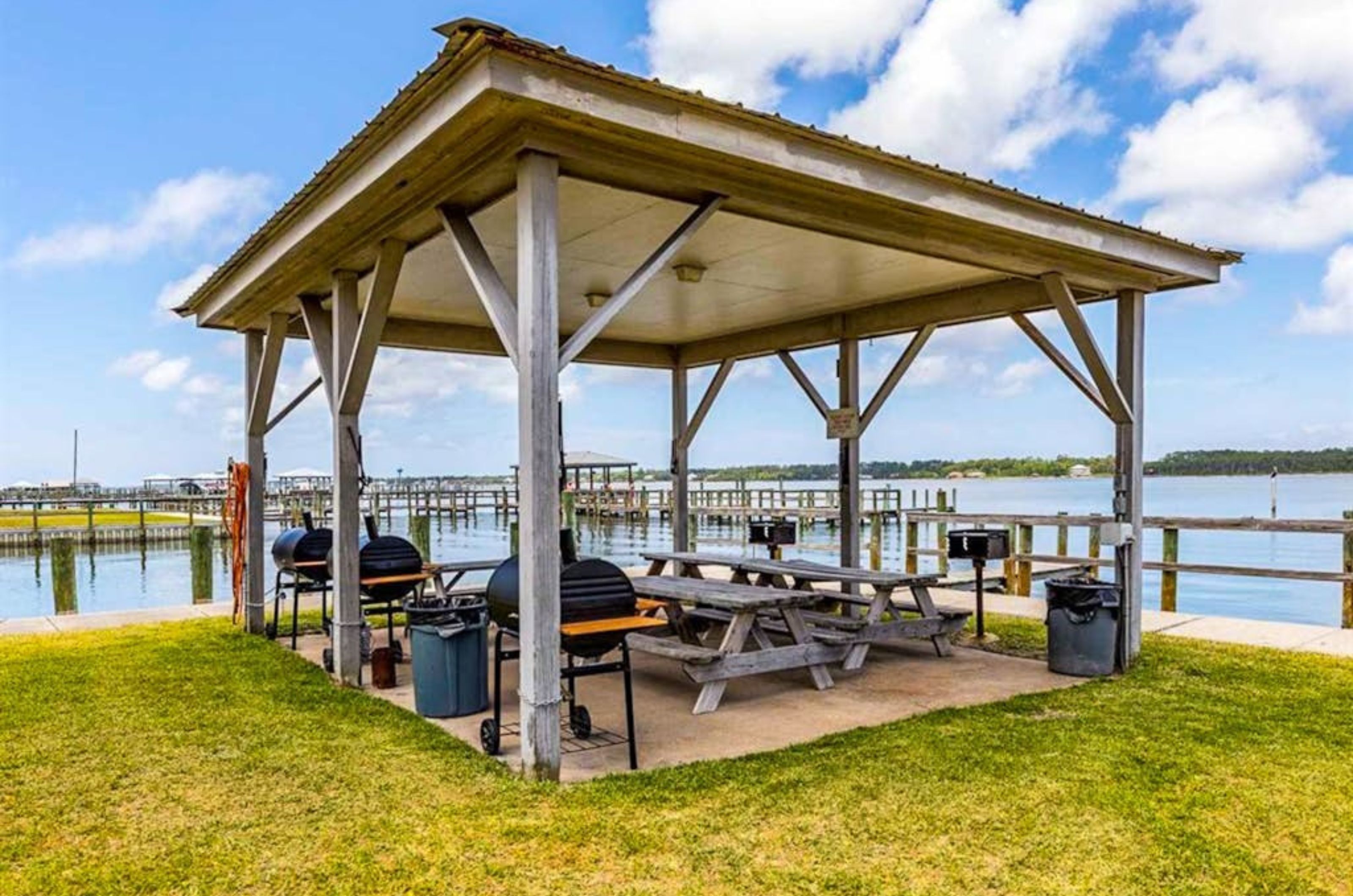 A wooden pavilion with grills and picnic tables next to the lagoon at Sea Oats 