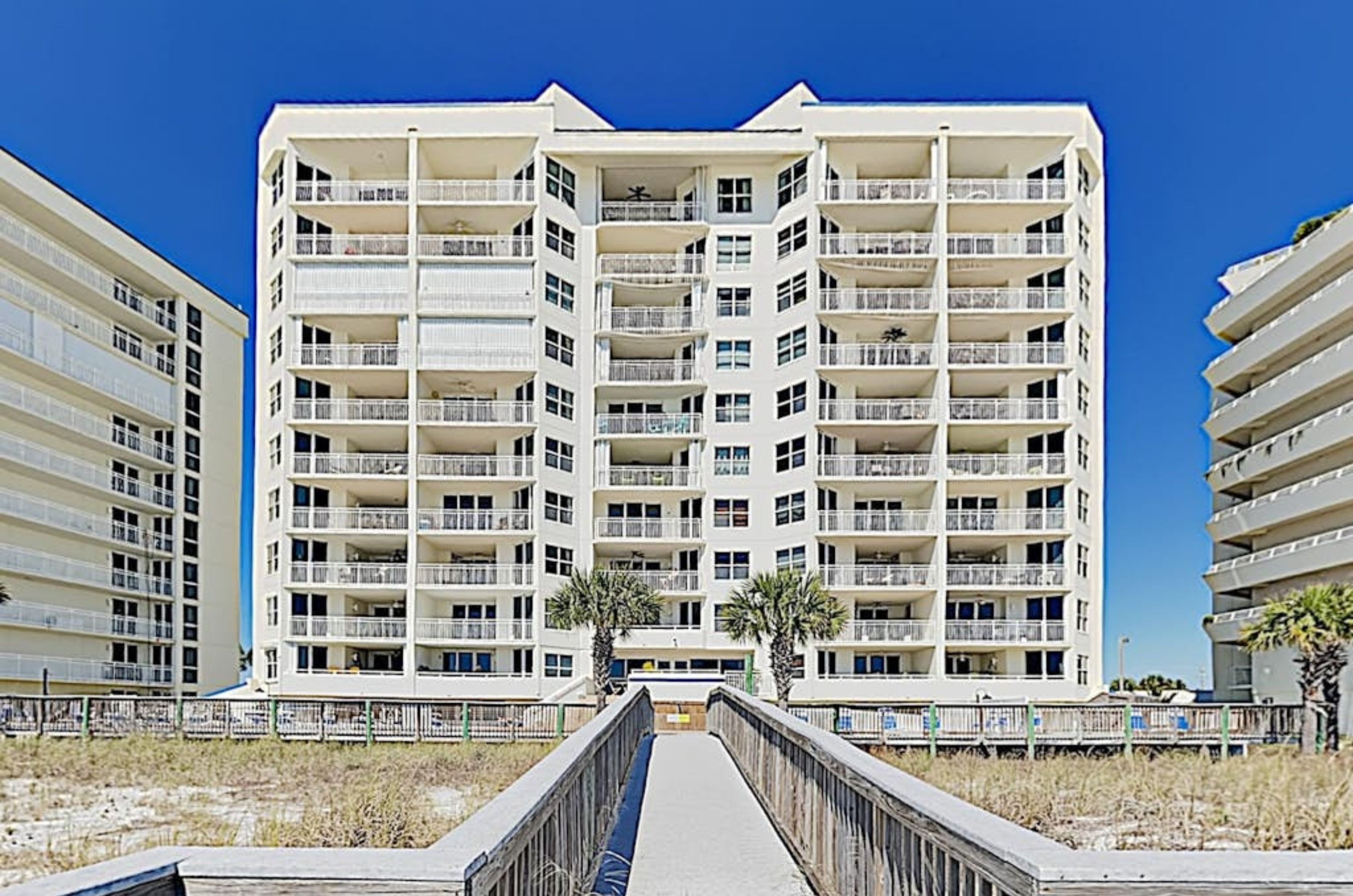 View of the beachside exterior of SeaSpray East with a wooden boardwalk leading to the Gulf 