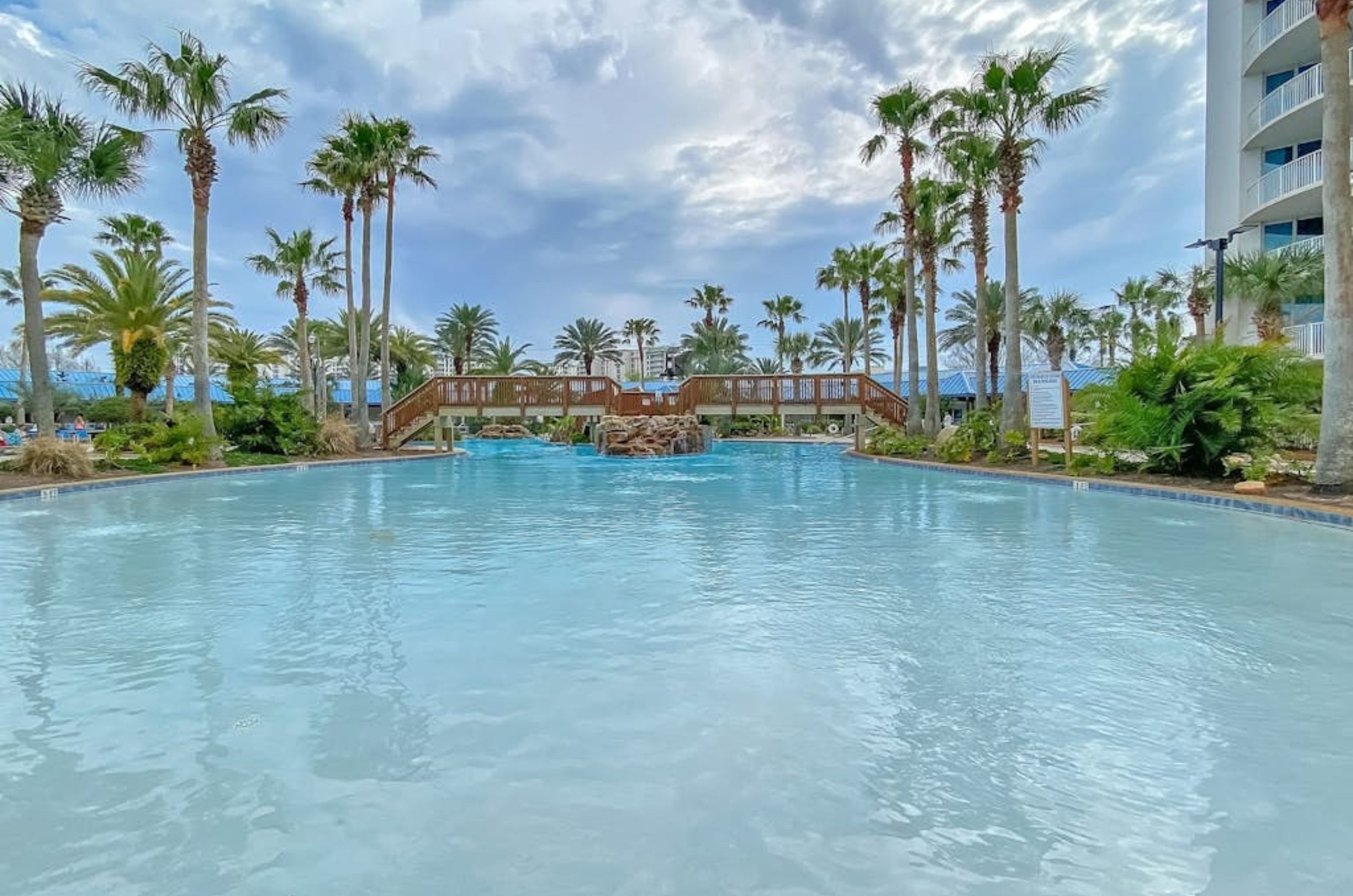 The large lagoon-style pool at the Palms of Destin with a wooden bridge crossing over