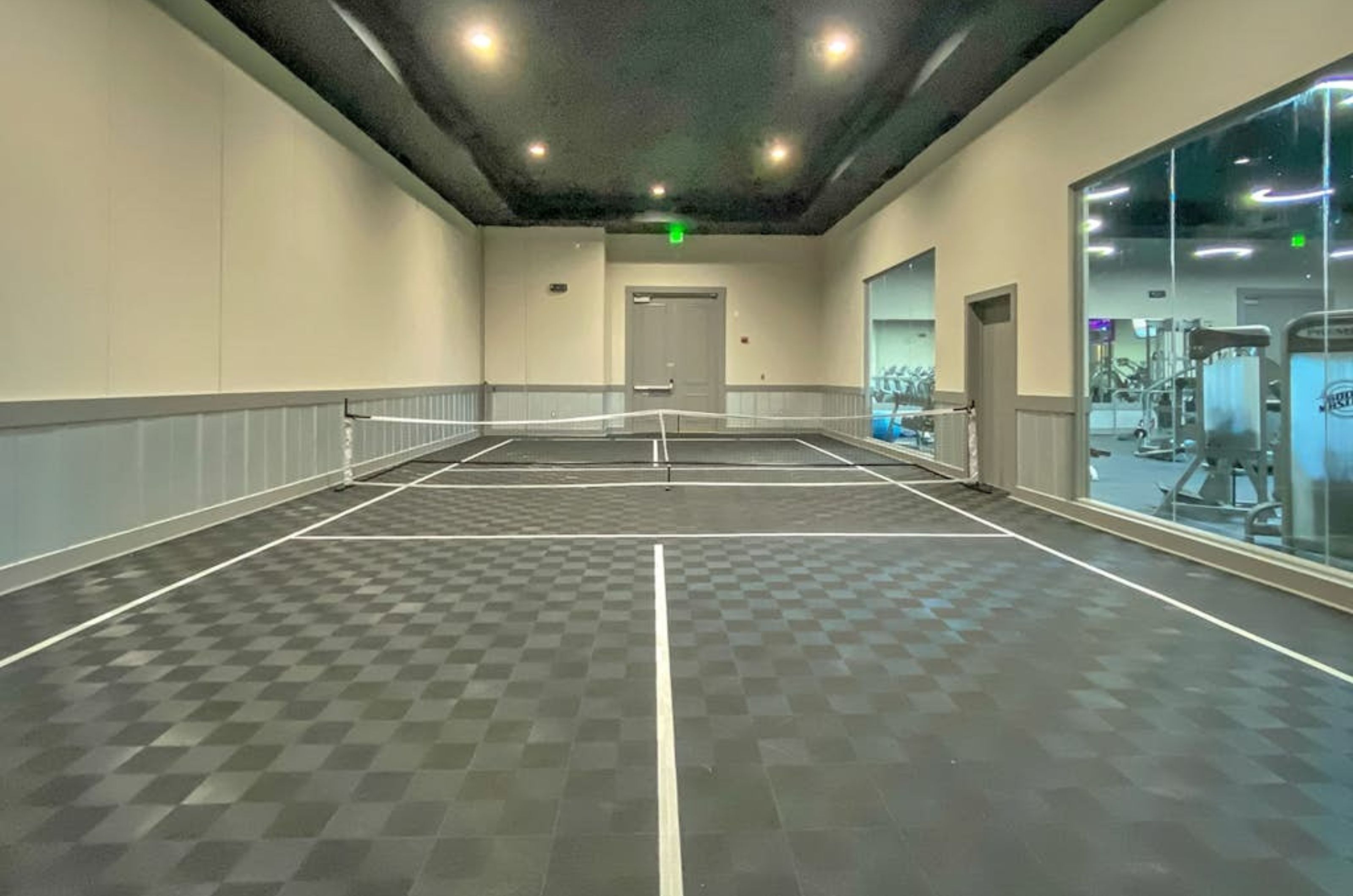 The indoor tennis court with windows overlooking the gym at the Palms of Destin 