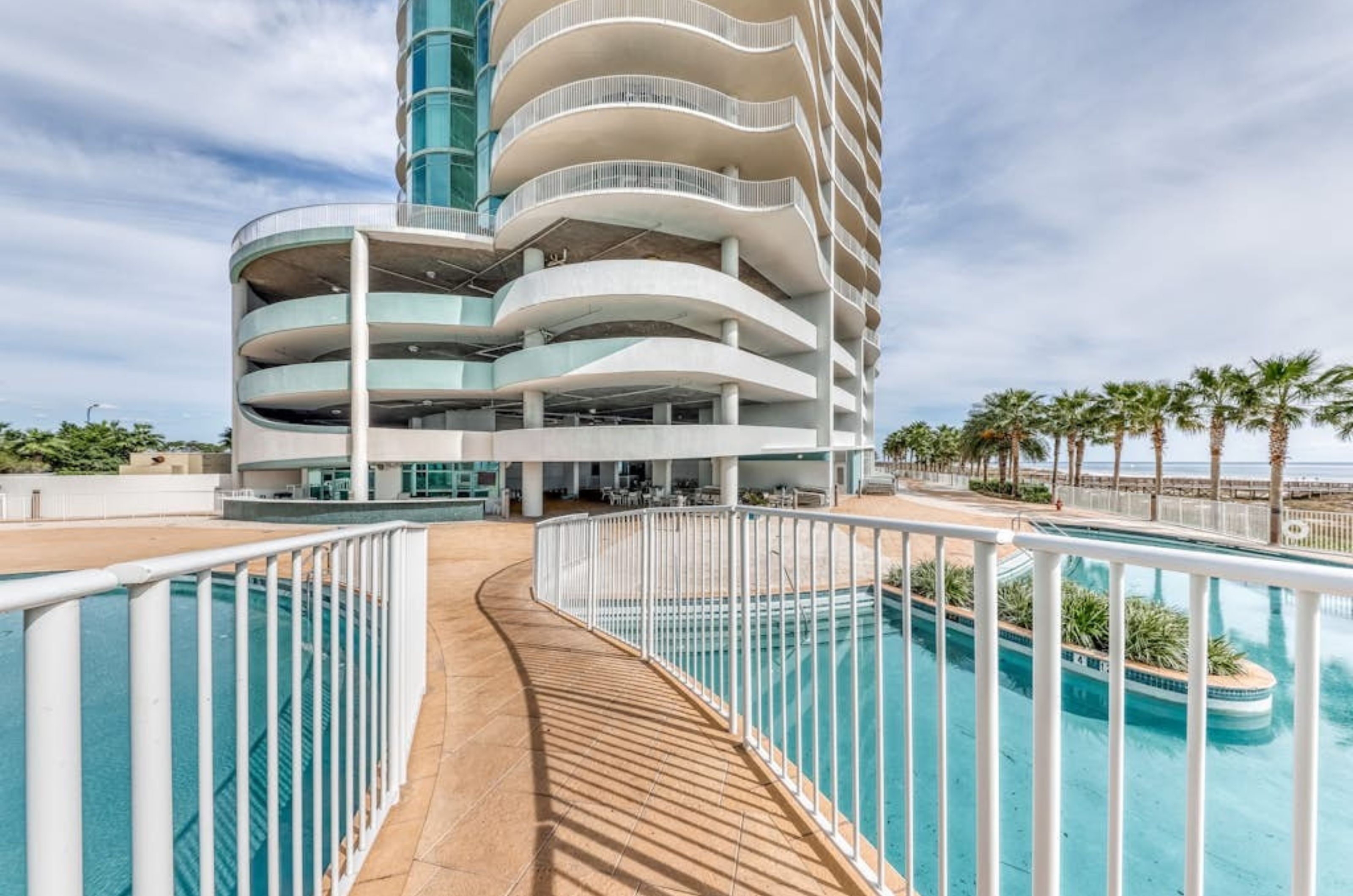 A bridge crossing over the outdoor pool in front of Turquoise Place and the parking garage	