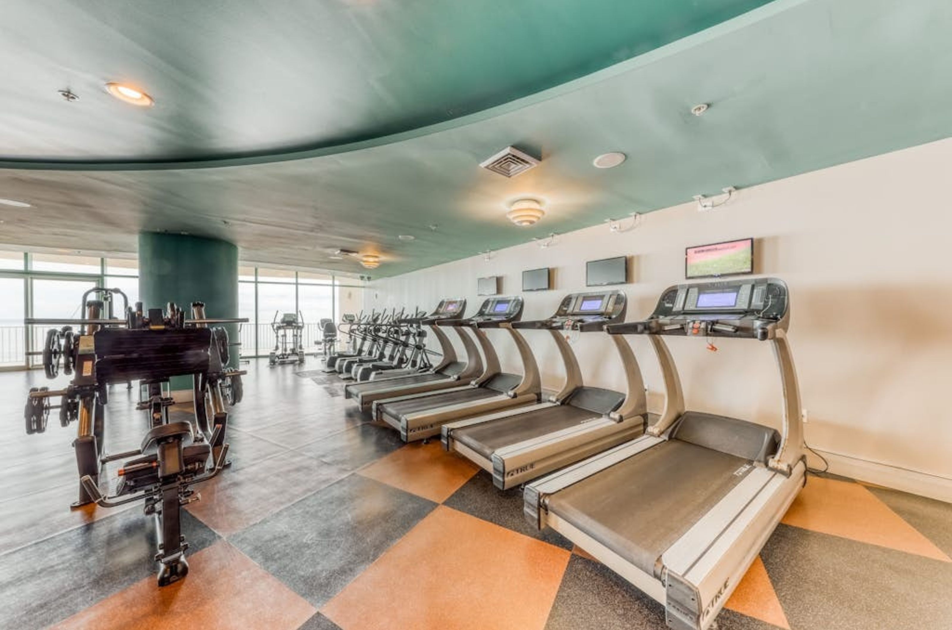 Cardio equipment in the fitness center at Turquoise Place next to floor to ceiling windows 