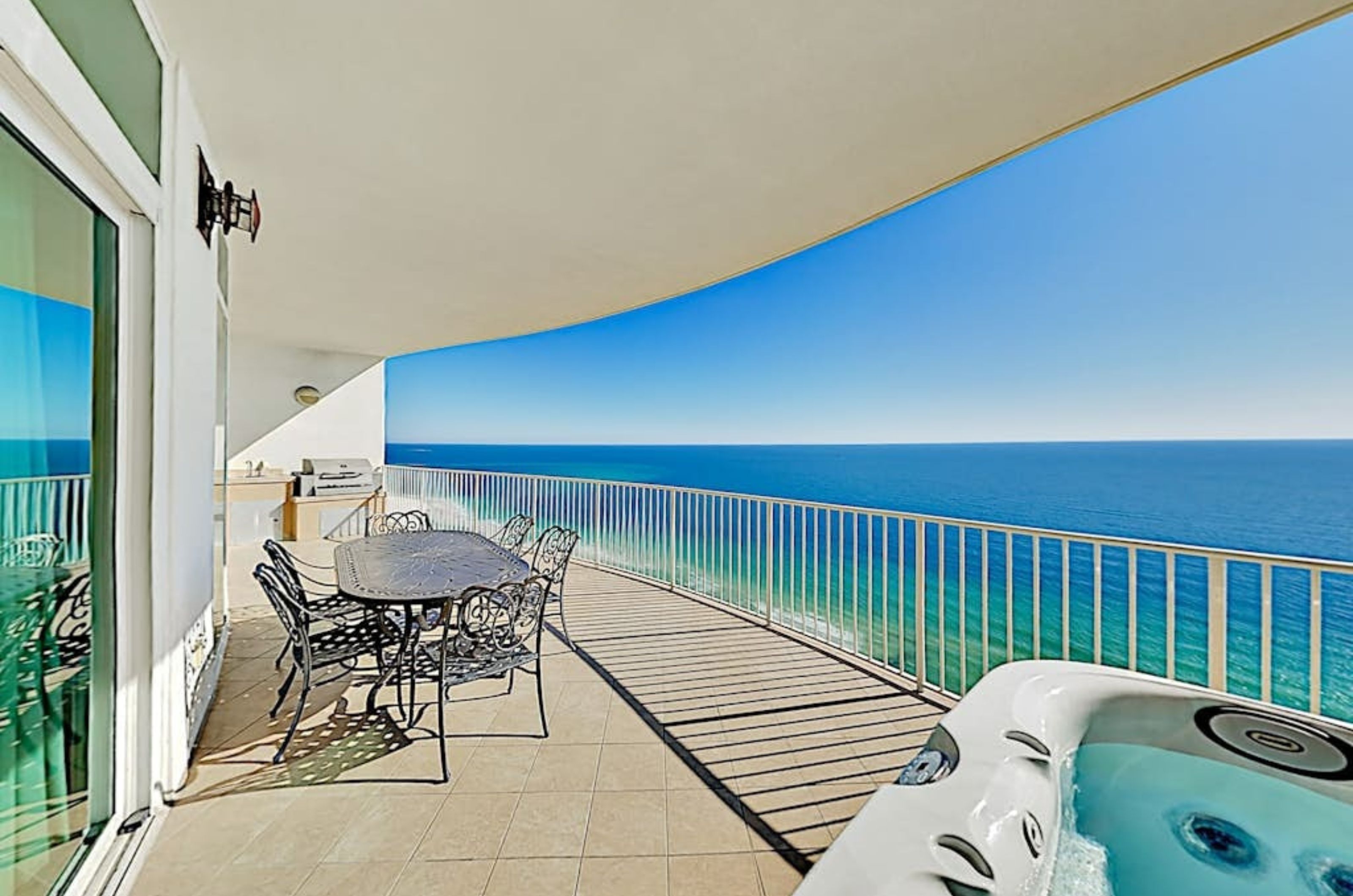 A private balcony at Turqouise Place with a hot tub lounge chairs and an outdoor kitchen 