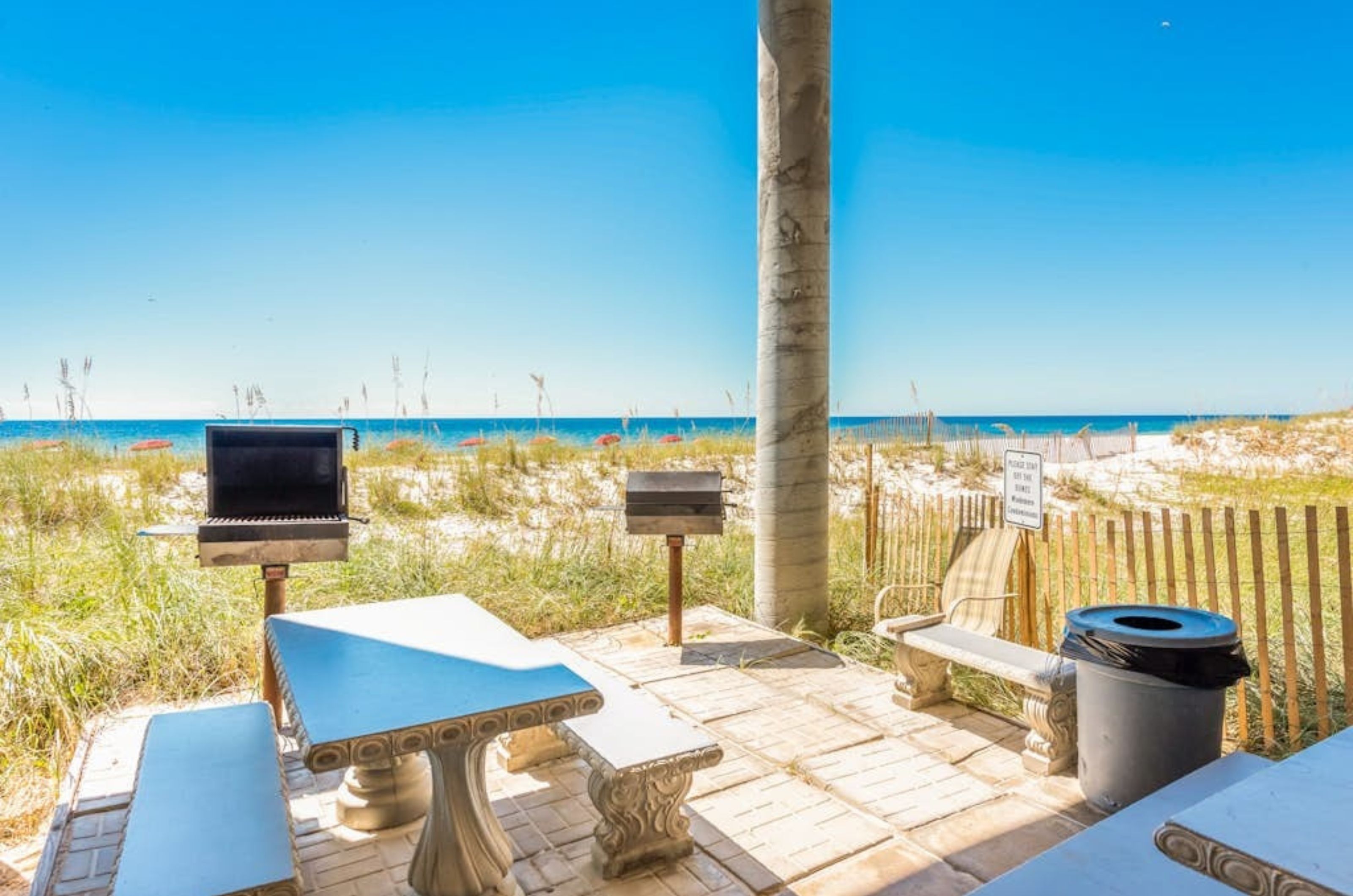 The outdoor grilling area with grills and picnic tables next to the beach 